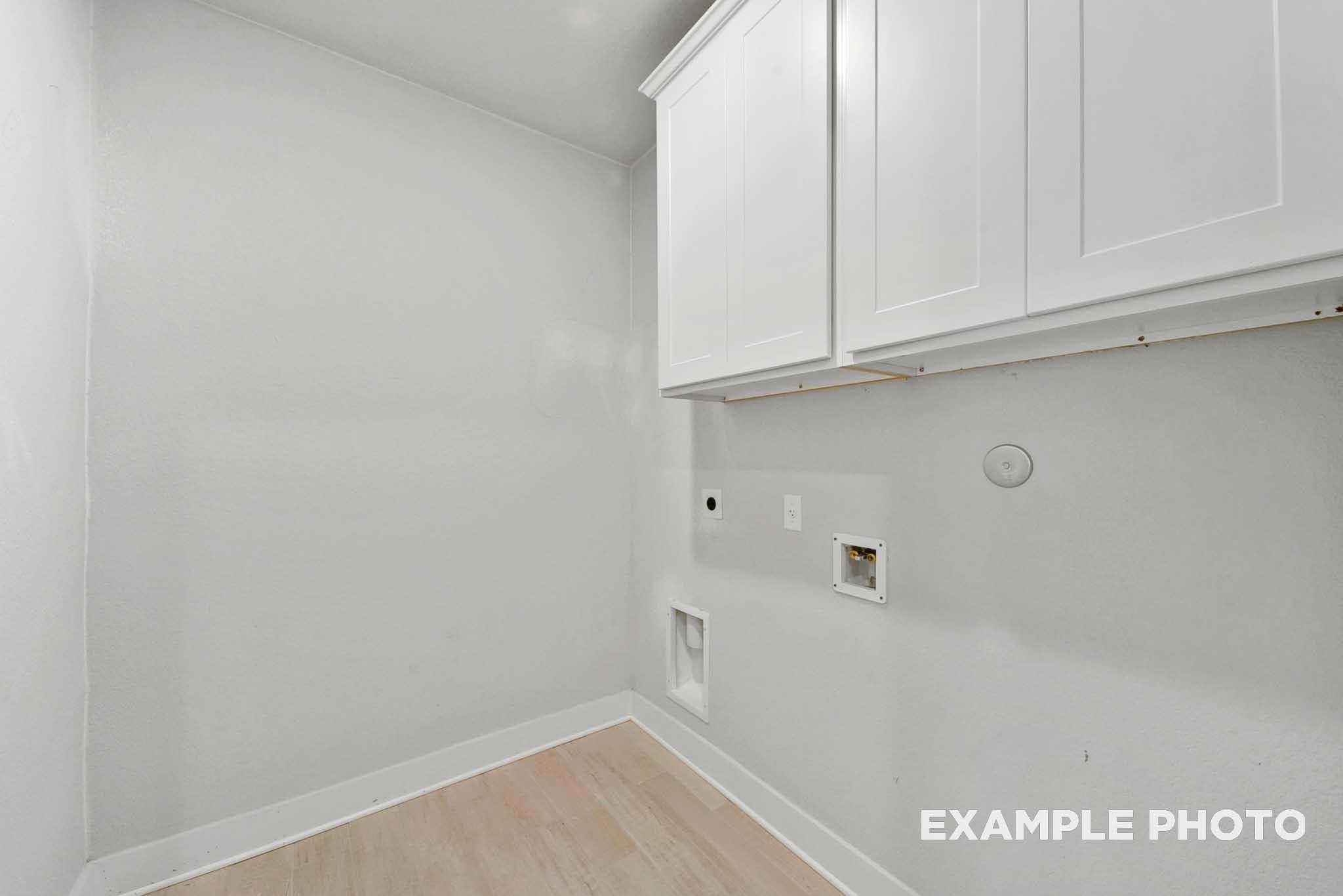 Modern laundry room with white cabinets, washer dryer hookups, and light wood floors in Davidson Homes The George A, Texas City