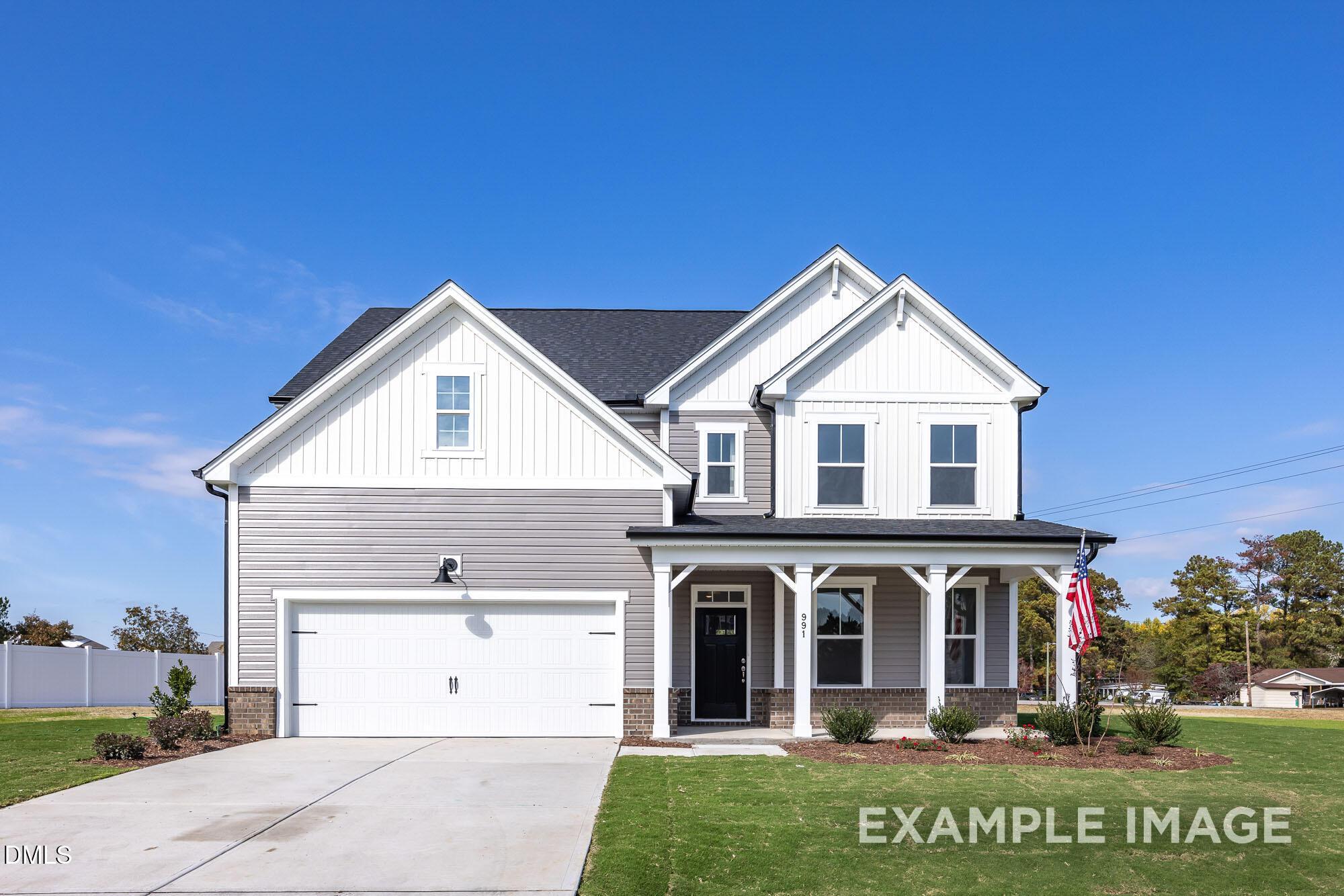 Two-story Hickory II B home by Davidson Homes in Wellers Knoll, Lillington, NC: gray siding, covered porch with flag, 2-car garage