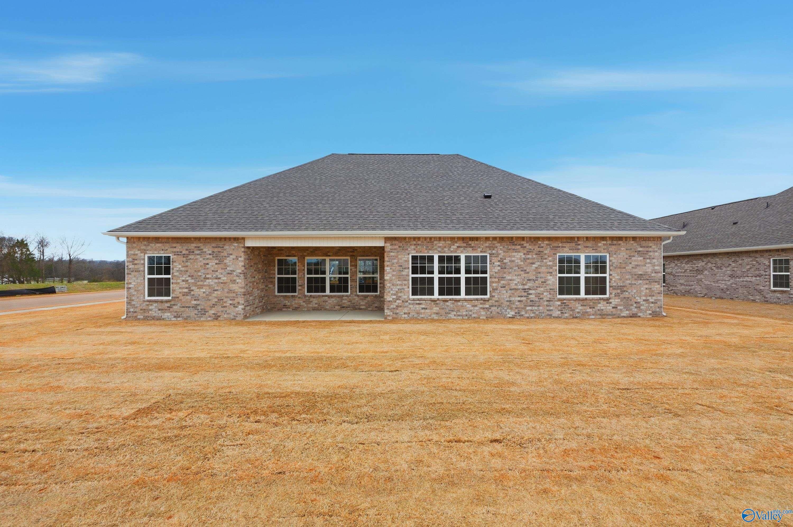 Back view of single-story brick The Finleigh home with covered patio, large windows, and grassy yard in Briercreek, Meridianville, Alabama