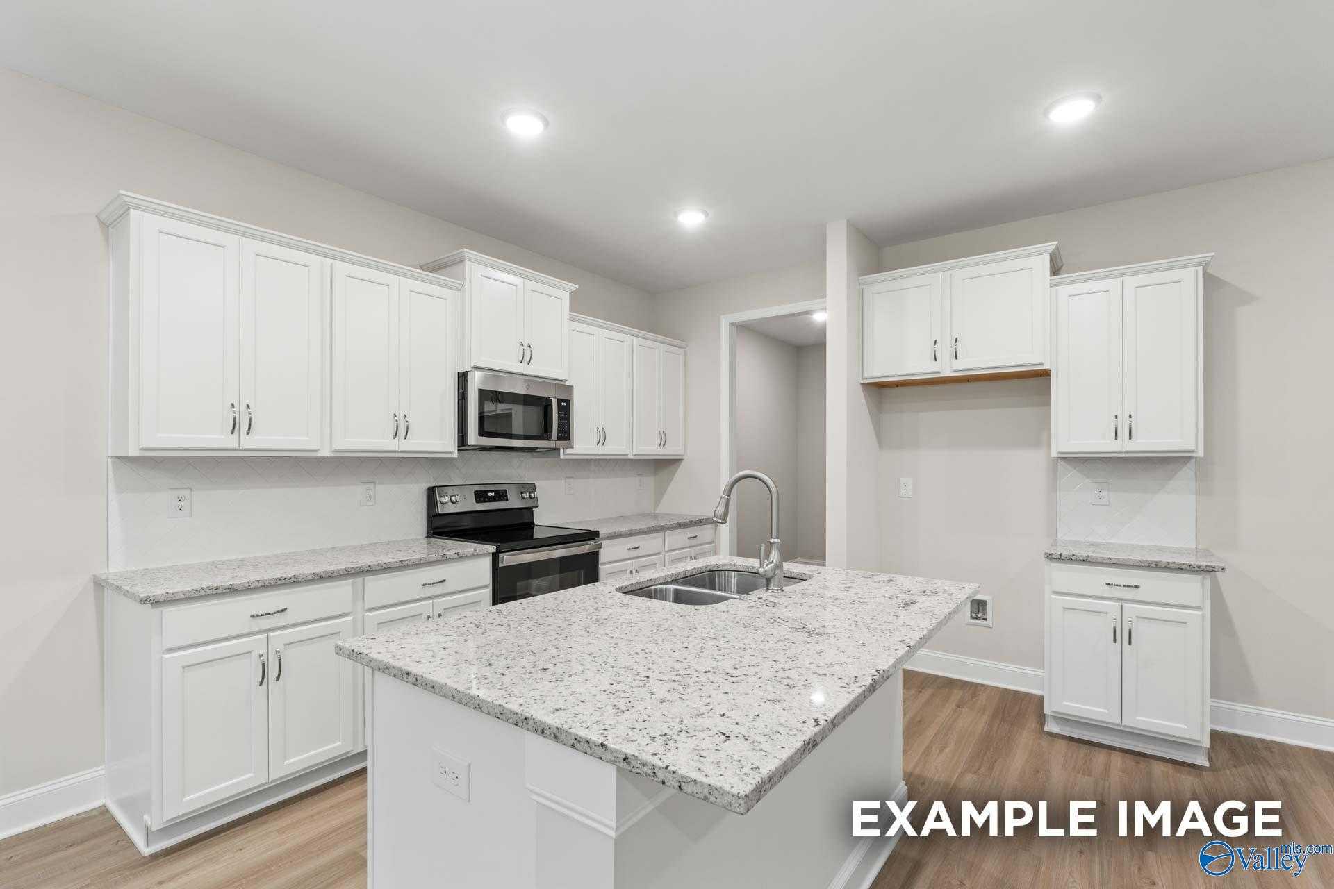 Modern open-concept kitchen with white cabinets, granite island, stainless appliances in Davidson Homes The Camden C, Huntsville AL