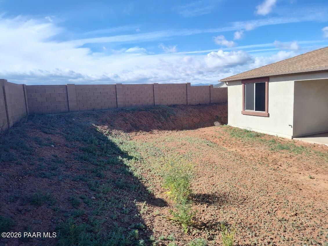 Private backyard with tan block walls, sparse desert landscaping, and covered patio in Davidson Homes The Harmony C, Prescott Valley, Arizona