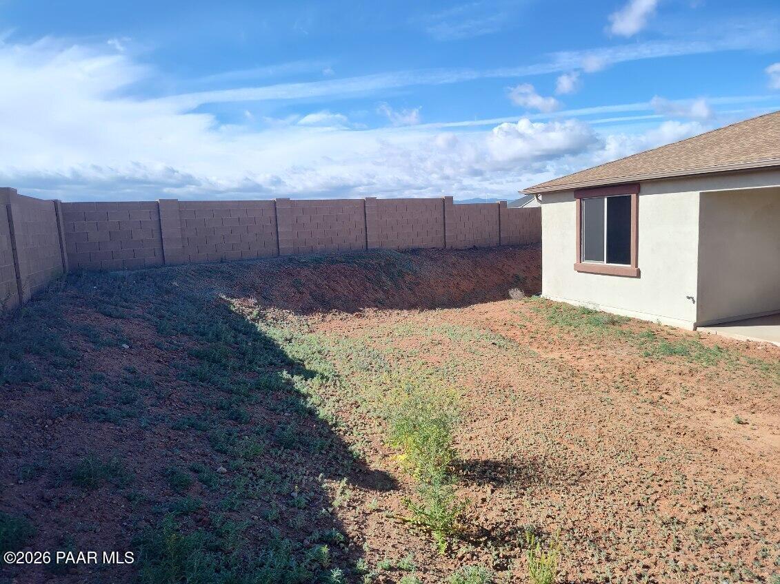 Private backyard with tan block walls, sparse desert landscaping, and covered patio in Davidson Homes The Harmony C, Prescott Valley, Arizona