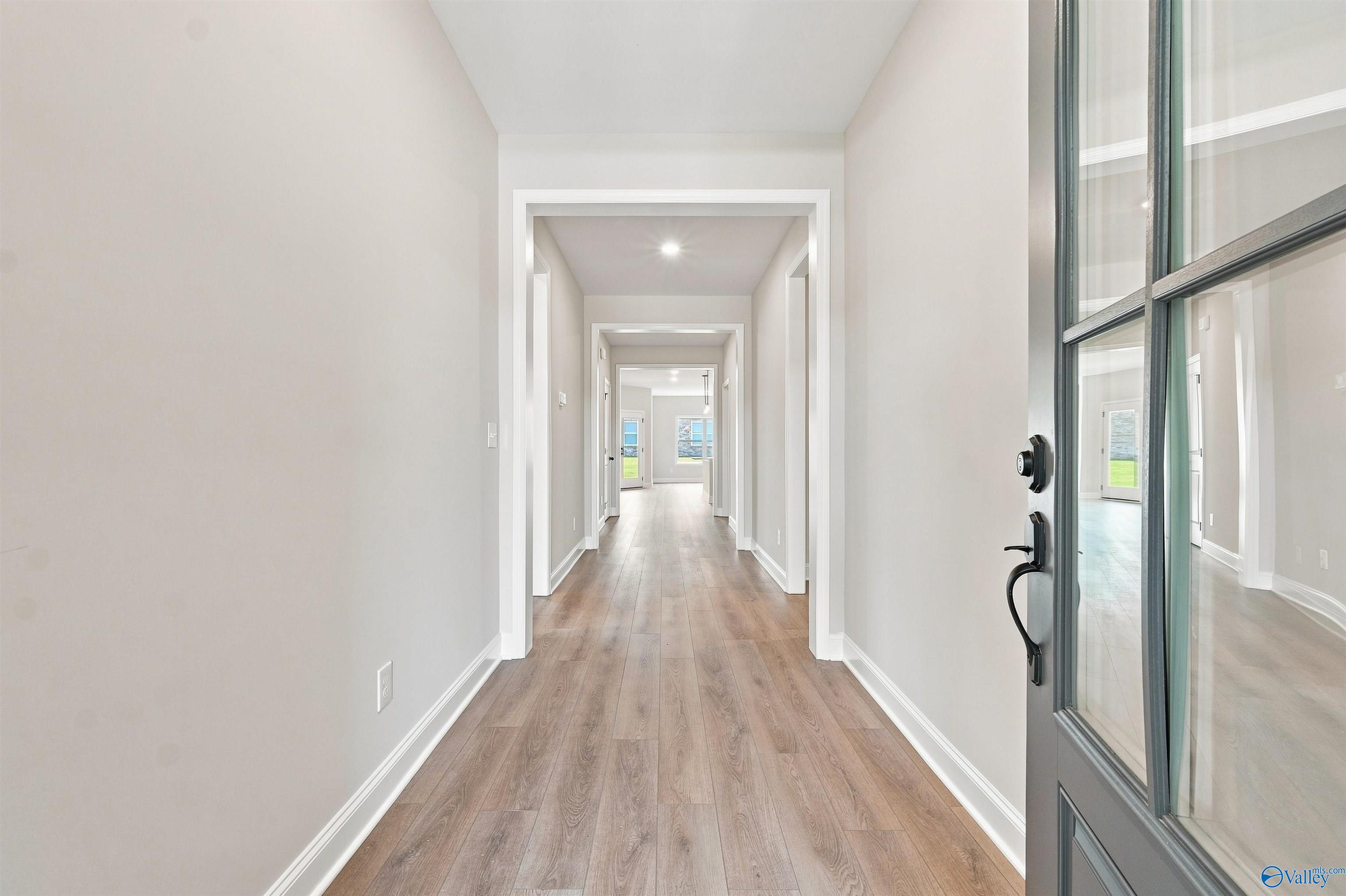 Bright entry foyer with glass-paneled front door and luxury vinyl plank flooring in Davidson Homes Everett B plan, Toney, AL