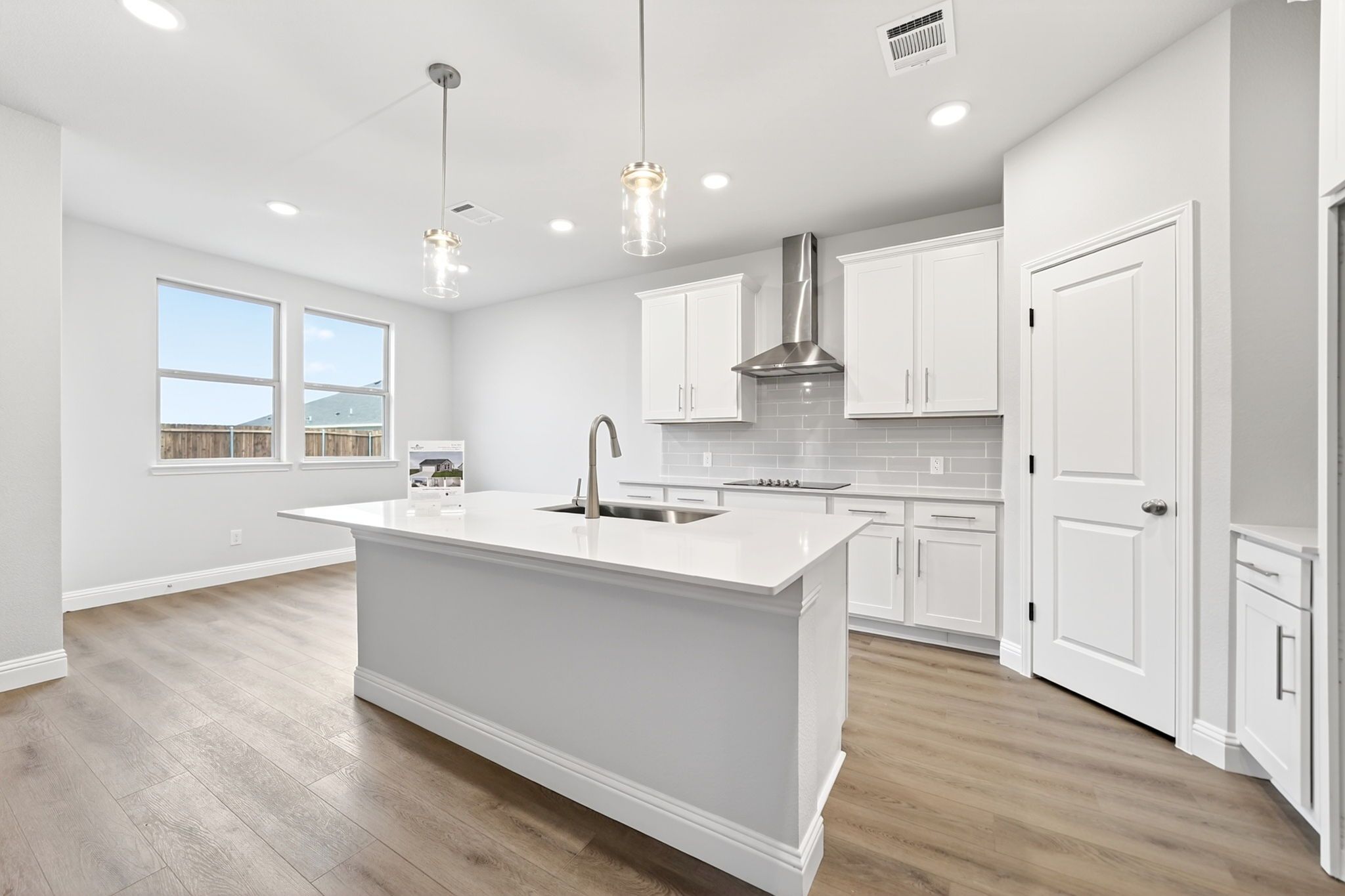 Modern kitchen in The Redbud design featuring white cabinetry, quartz island, and stainless steel appliances in Josephine, TX.