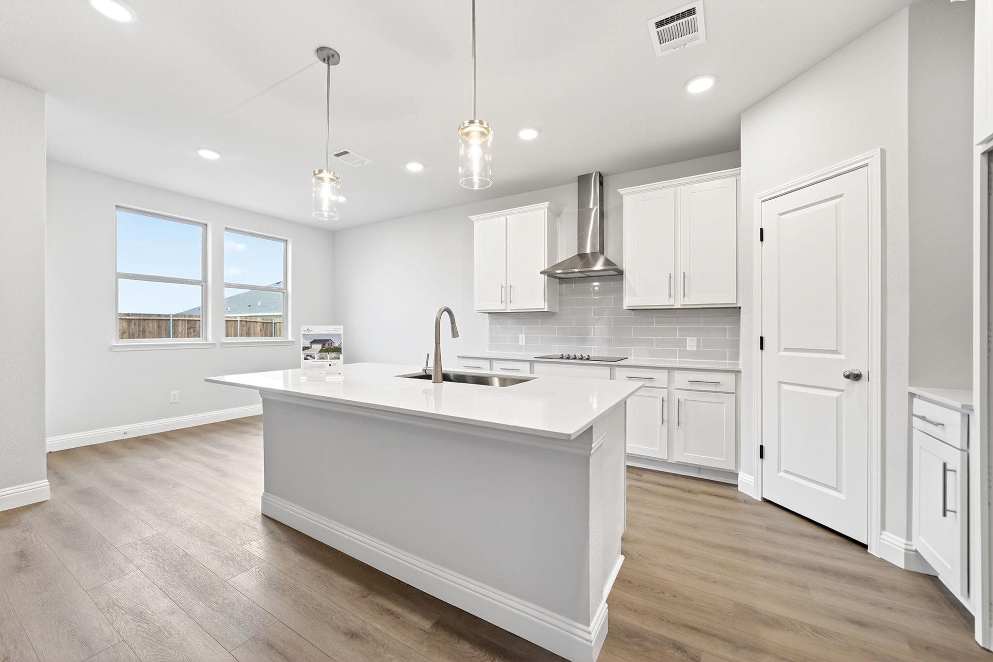 Modern kitchen in The Redbud design featuring white cabinetry, quartz island, and stainless steel appliances in Josephine, TX.