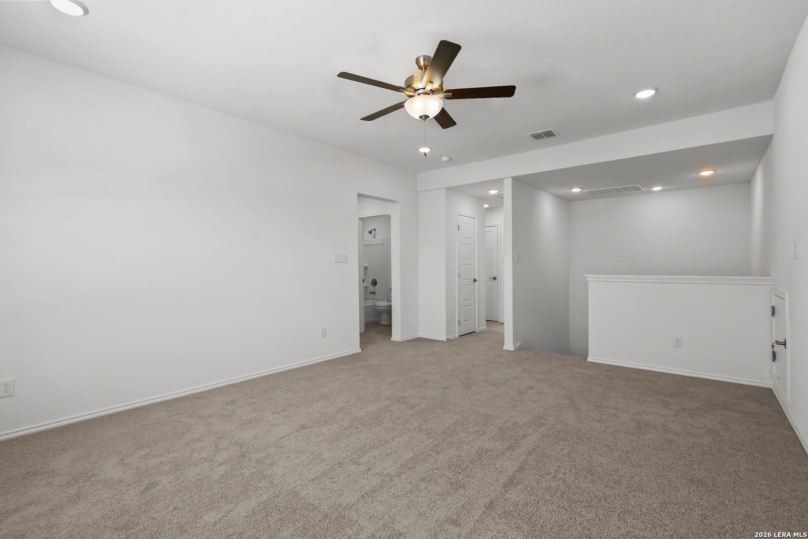 Bright upstairs loft with beige carpet, ceiling fan, and bathroom doorway in Davidson Homes The Sequoia B, San Antonio