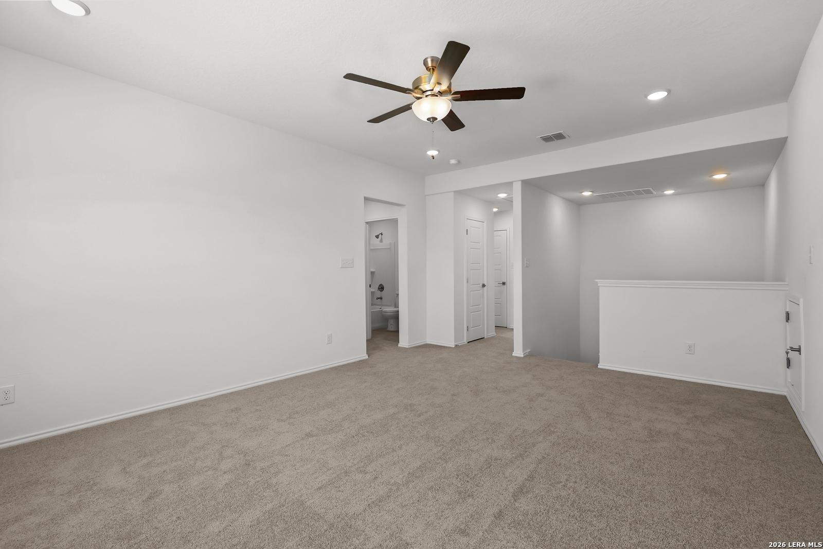Bright upstairs loft with beige carpet, ceiling fan, and bathroom doorway in Davidson Homes The Sequoia B, San Antonio