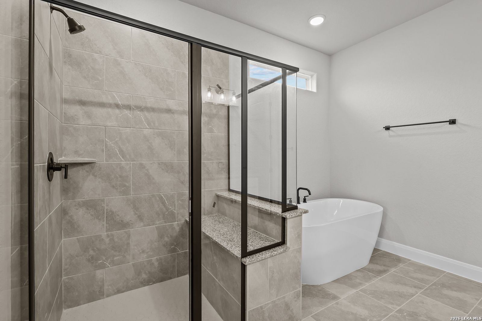 Modern master bathroom with frameless glass shower, freestanding tub, and granite vanity in Davidson Homes The Belmont H, Castroville, Texas