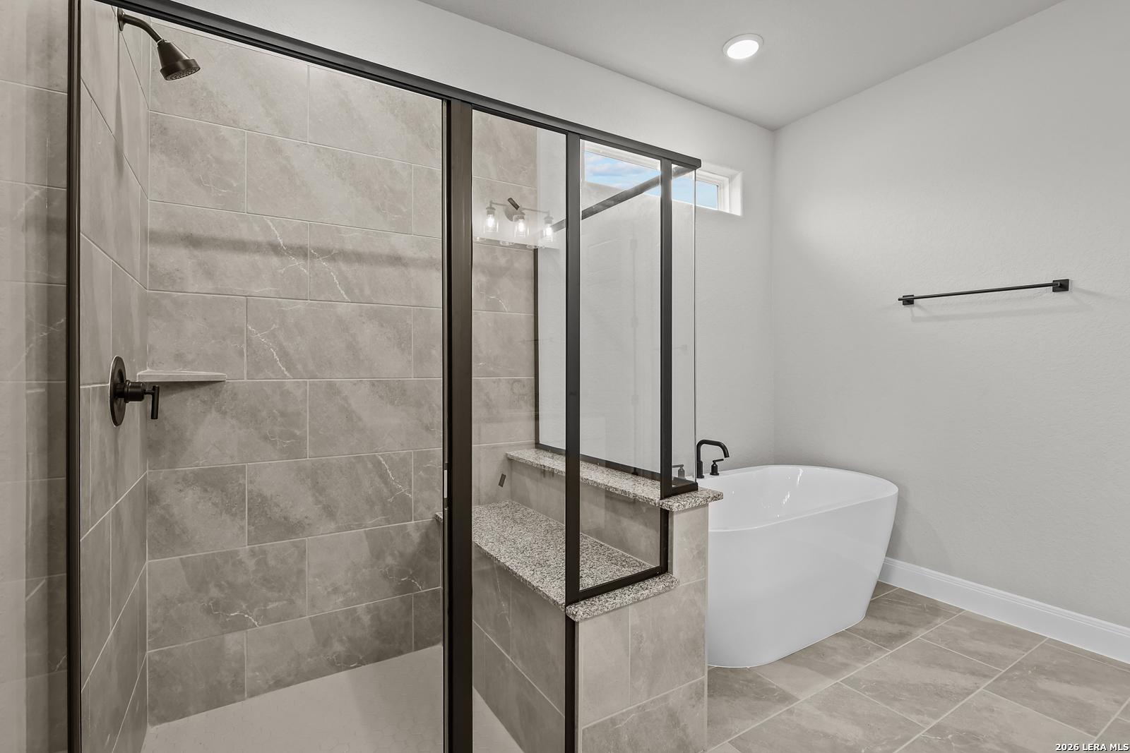 Modern master bathroom with frameless glass shower, freestanding tub, and granite vanity in Davidson Homes The Belmont H, Castroville, Texas