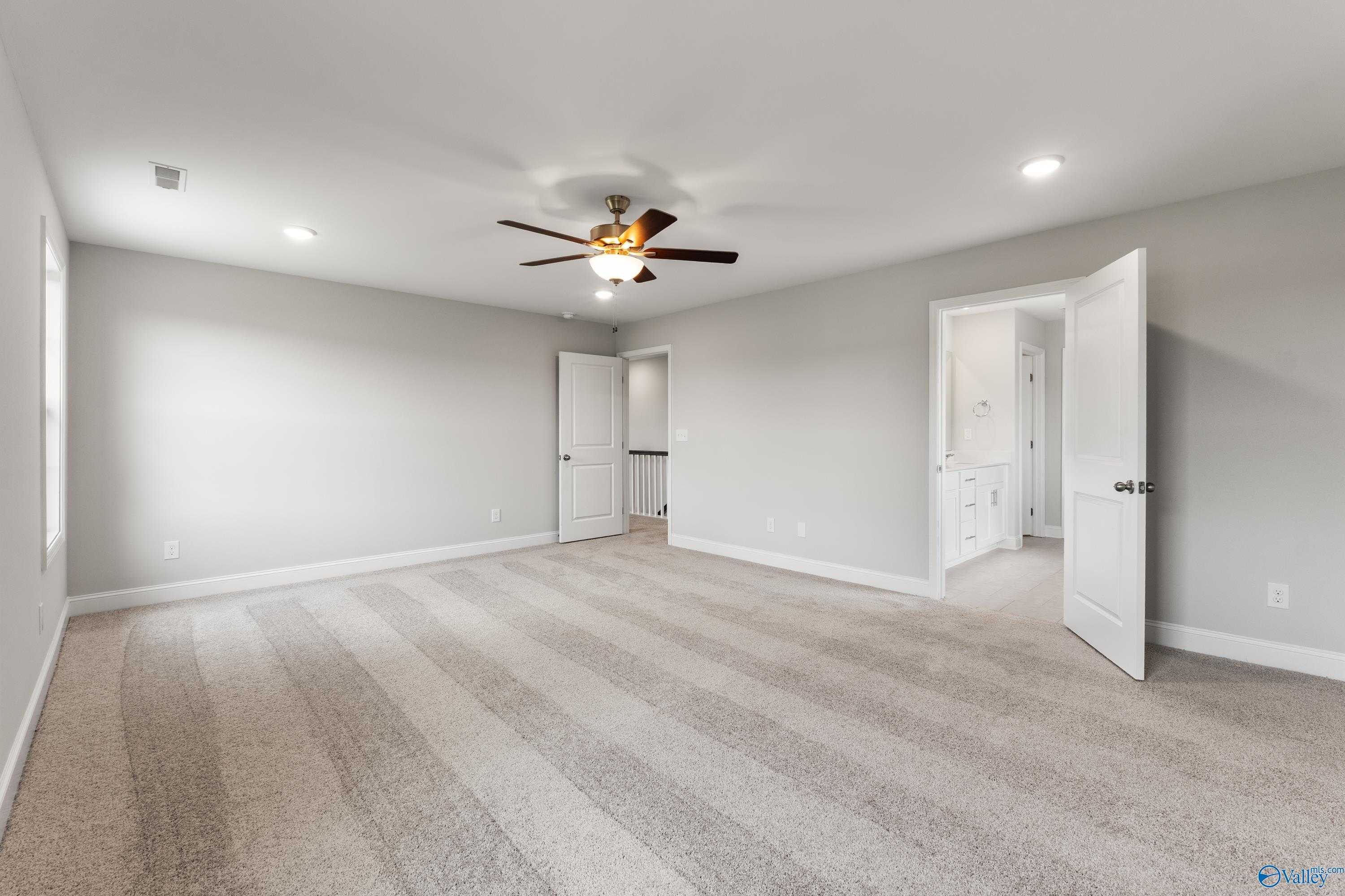 Spacious upstairs bonus room with ceiling fan, beige carpet, and adjacent bathroom in Davidson Homes The Madison A, Toney, Alabama