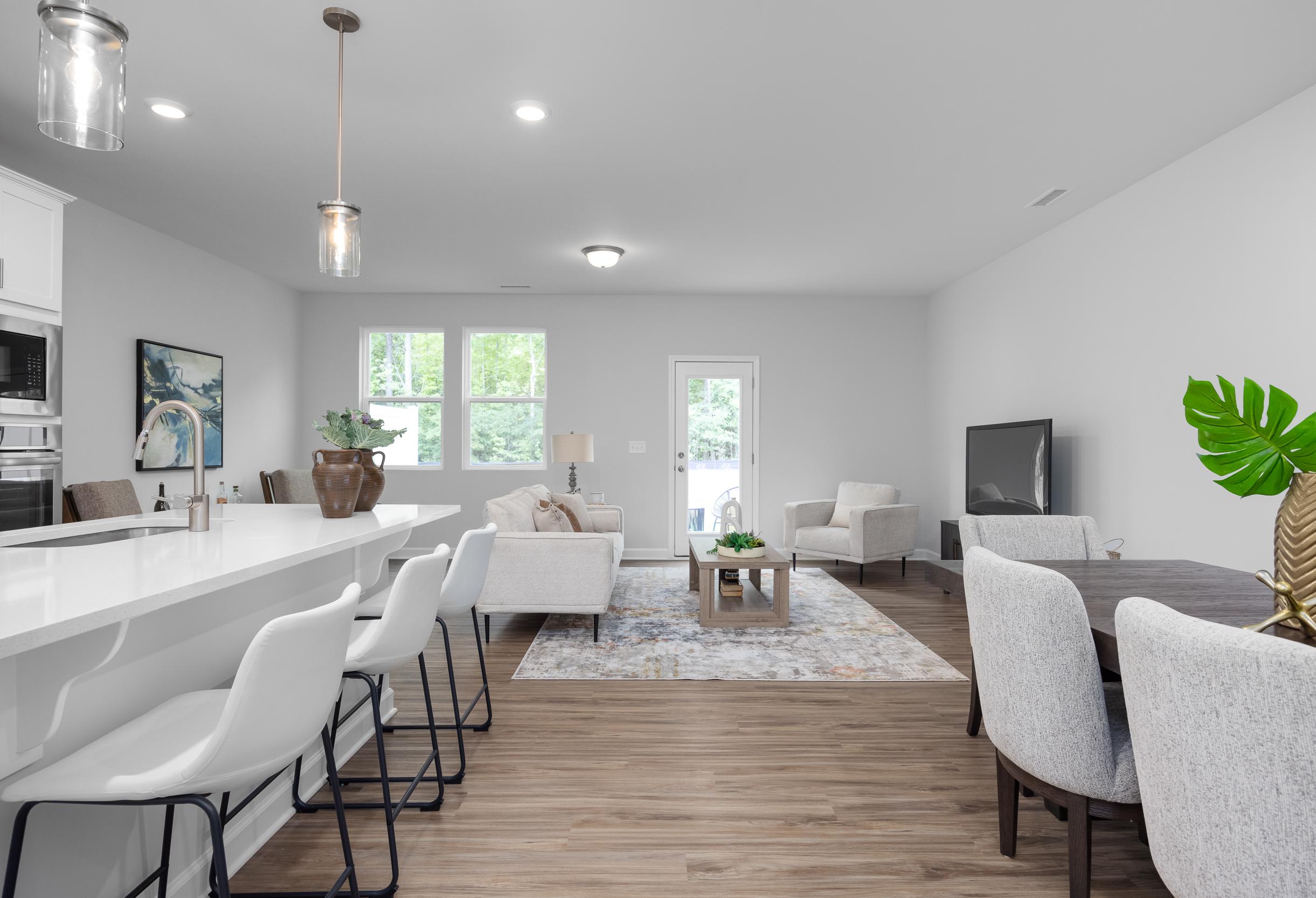 Open-concept kitchen and living area in The Warren by Davidson Homes featuring a spacious island and modern dining space.