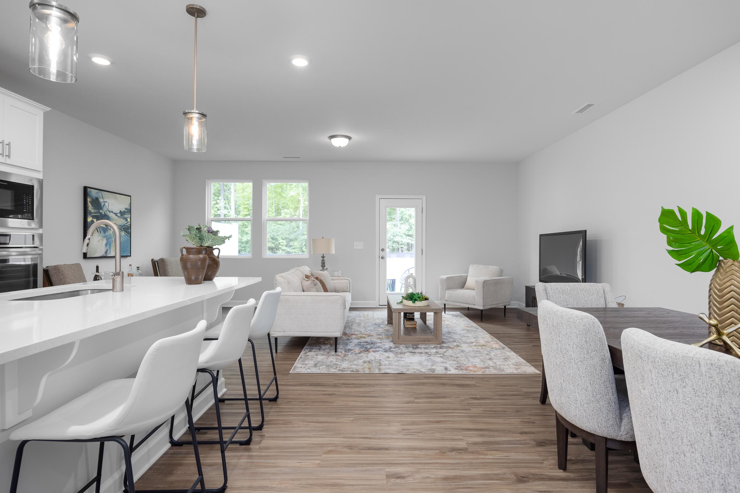 Open-concept kitchen and living area in The Warren by Davidson Homes featuring a spacious island and modern dining space.