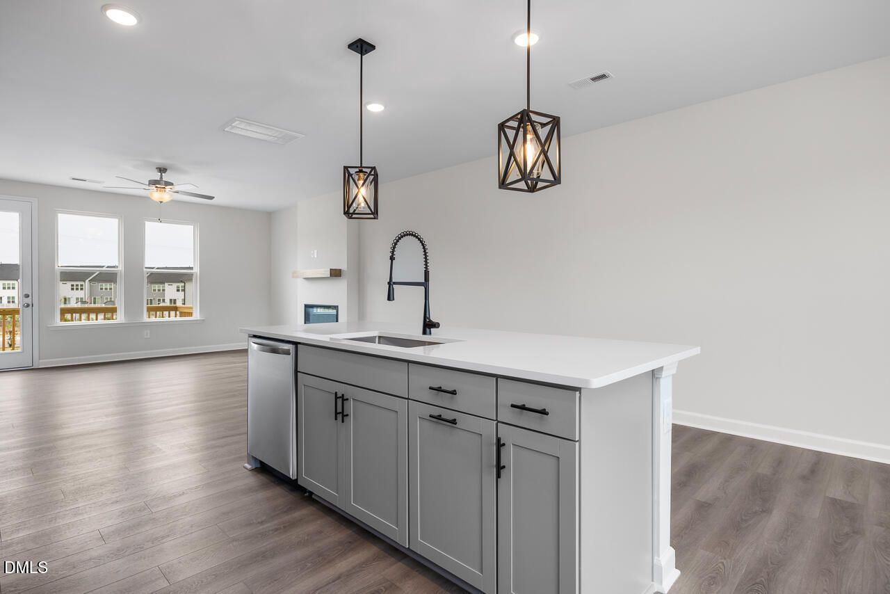 Modern kitchen island with gray cabinetry and pendant lighting in The Mitchell floor plan, Forestville Yard, Knightdale, NC.
