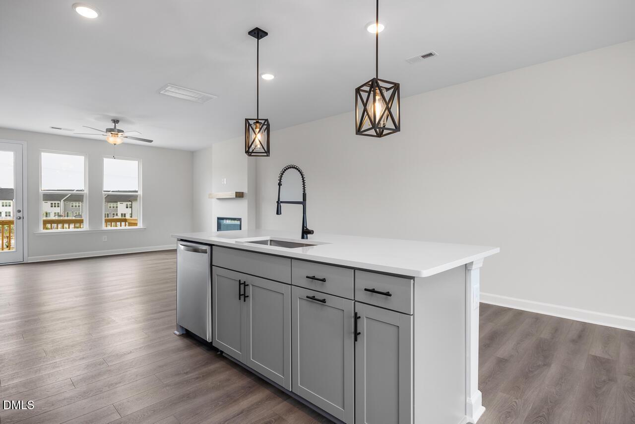 Modern kitchen island with gray cabinetry and pendant lighting in The Mitchell floor plan, Forestville Yard, Knightdale, NC.