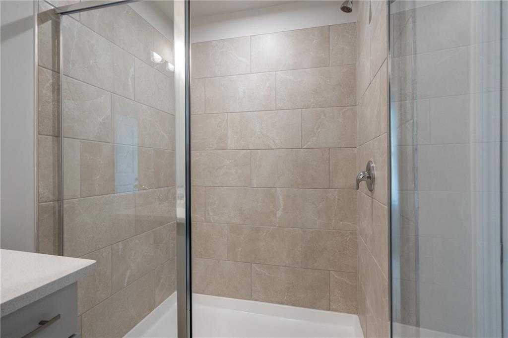 Modern frameless glass shower with neutral tile walls in master bath, Davidson Homes The Cary A, Kennesaw GA