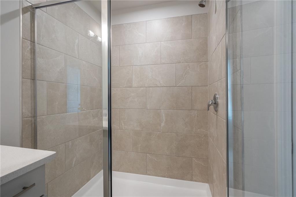Frameless glass shower with beige porcelain tile walls and rainfall head in master bath, The Cary A by Davidson Homes, Kennesaw GA