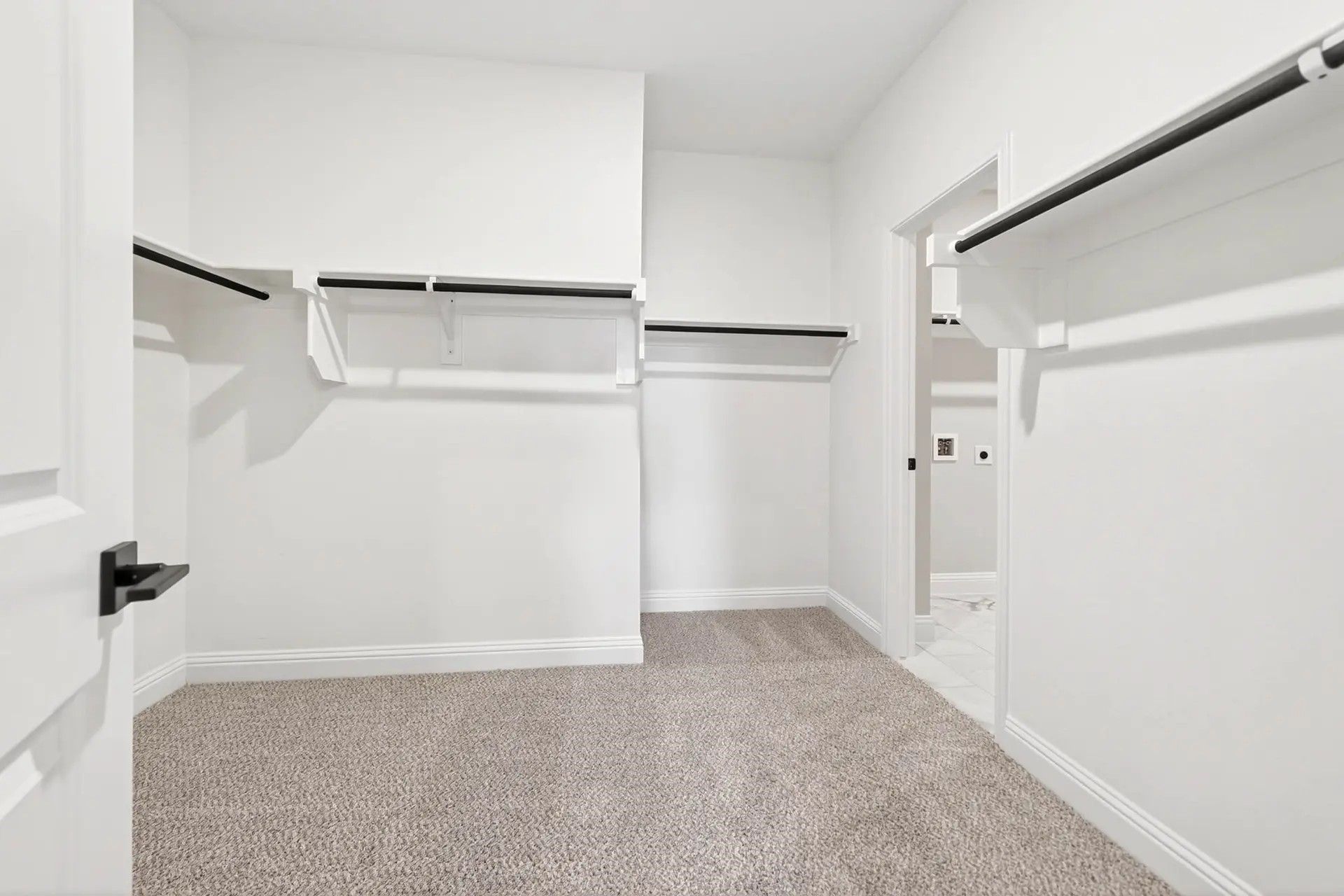 Spacious walk-in closet with carpeted flooring in The Holly C floor plan by Davidson Homes in Heartland, Texas.