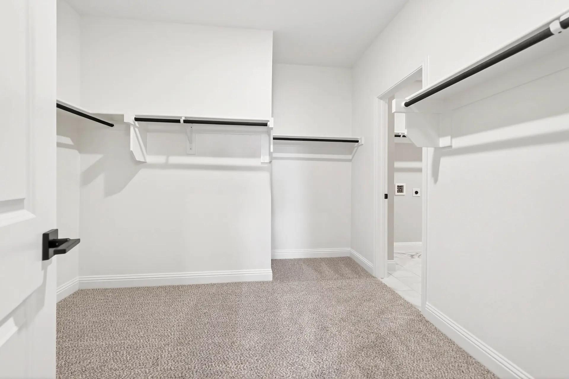 Spacious walk-in closet with carpeted flooring in The Holly C floor plan by Davidson Homes in Heartland, Texas.