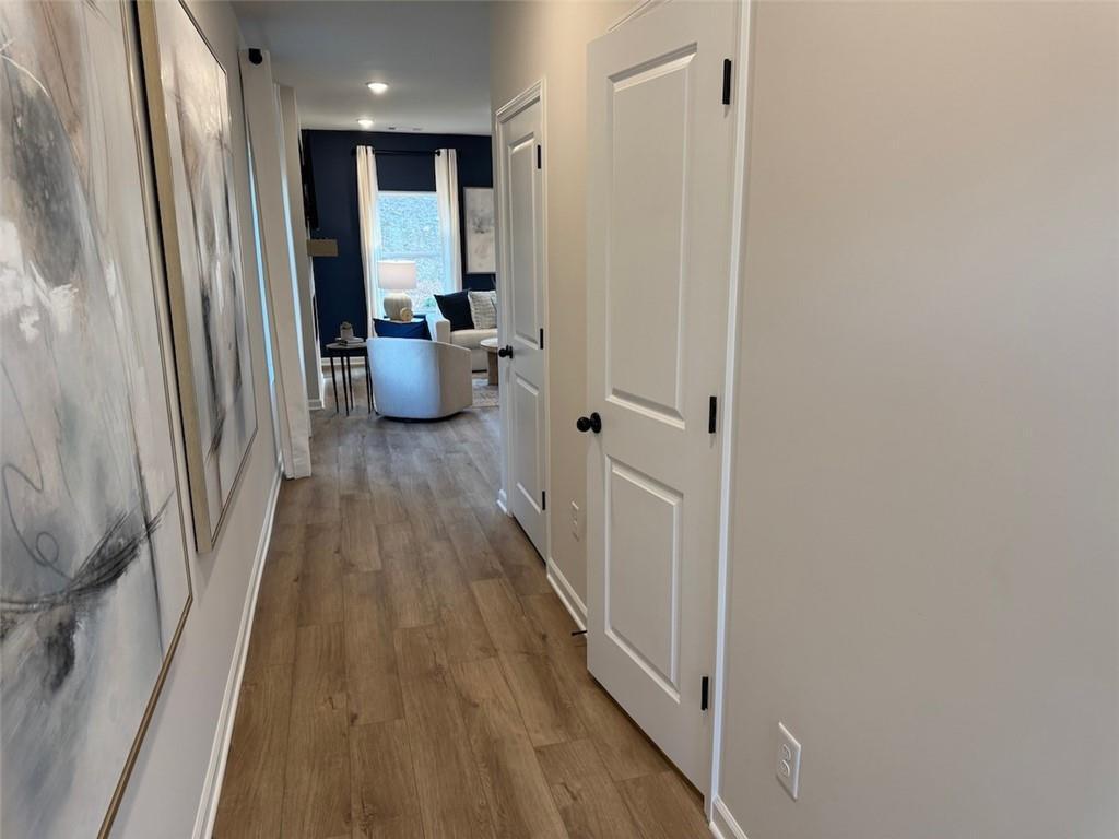 Elegant hallway with hardwood floors, white doors, and navy blue living room with armchair and abstract art in The Hartwell A, Canton, GA