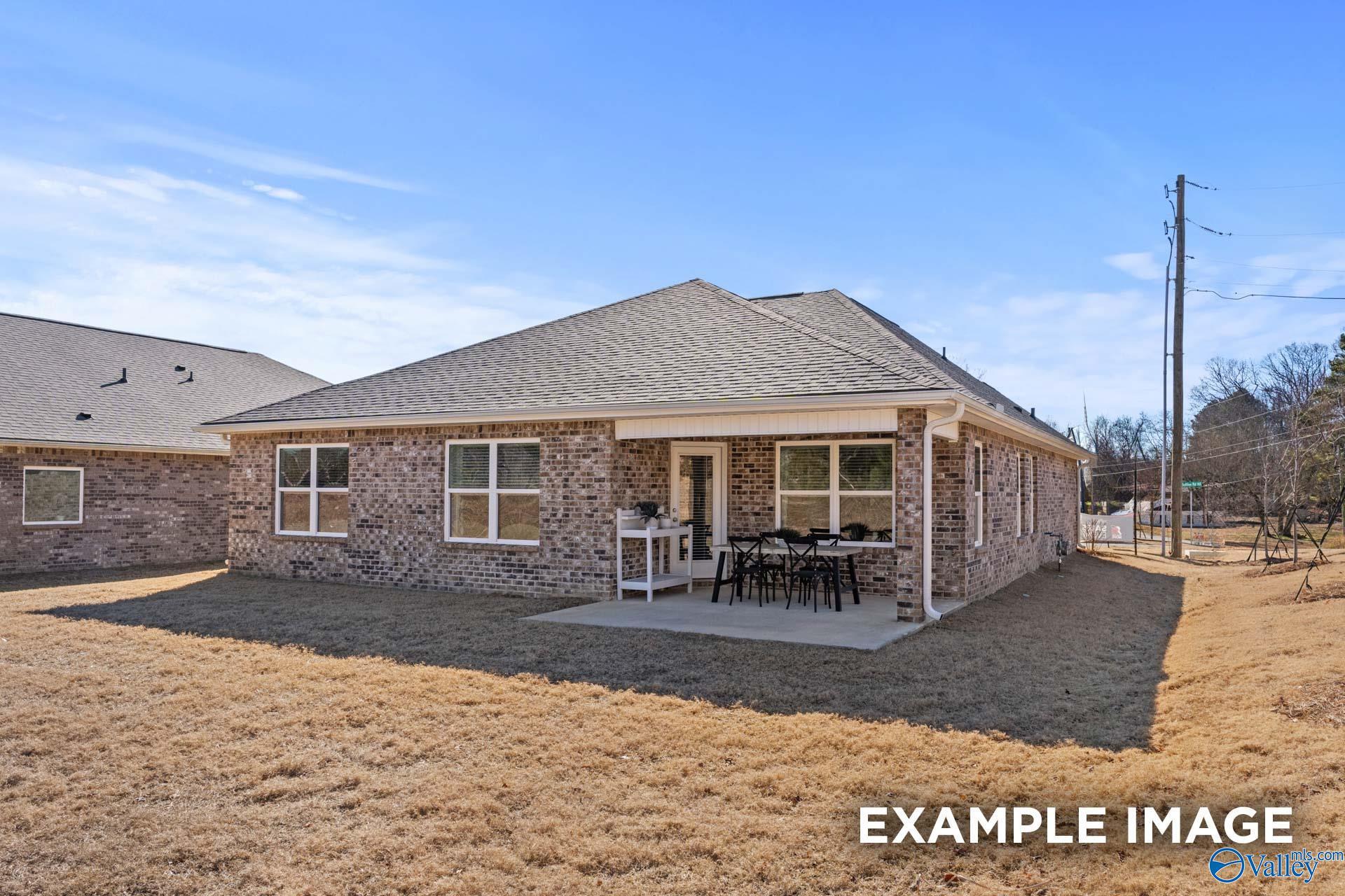Covered back patio with white railing and patio furniture on single-story brick home in Creek Grove, New Market, Alabama