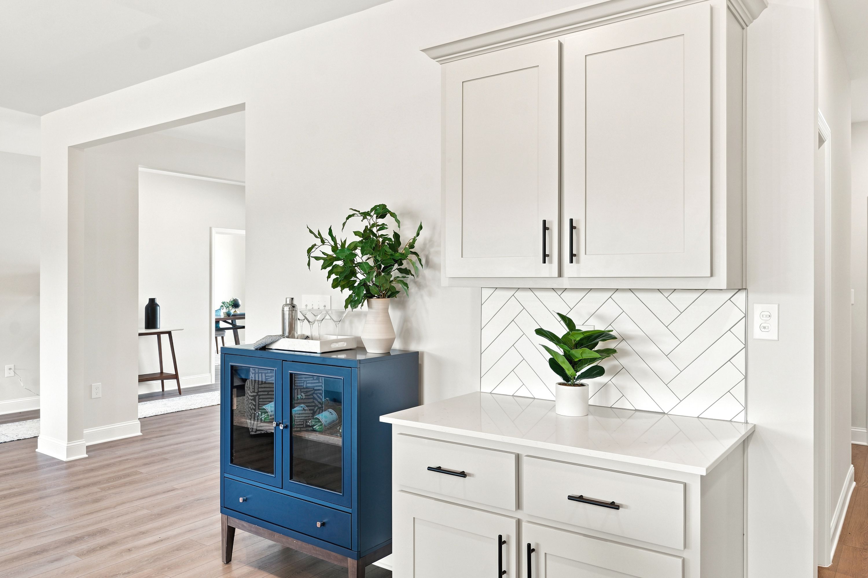 Modern butler's pantry at Riverton Preserve in Huntsville, AL featuring white cabinets and blue accent furniture.