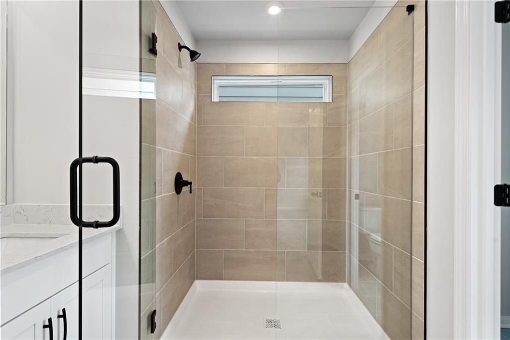 Modern master bathroom featuring frameless glass shower, beige subway tiles, and white double vanity in Davidson Homes The Marion A, Kennesaw, GA