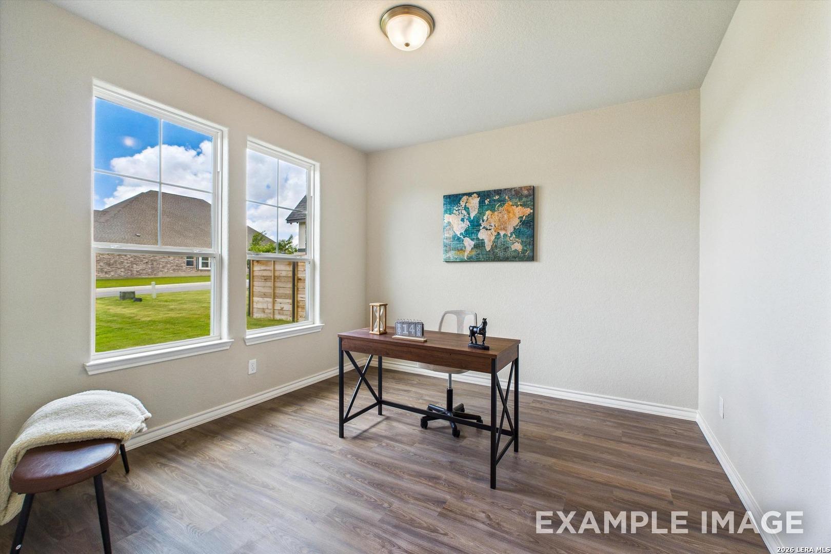 Bright home office with wood floors and world map wall art in The Foster F floor plan by Davidson Homes in Castroville.