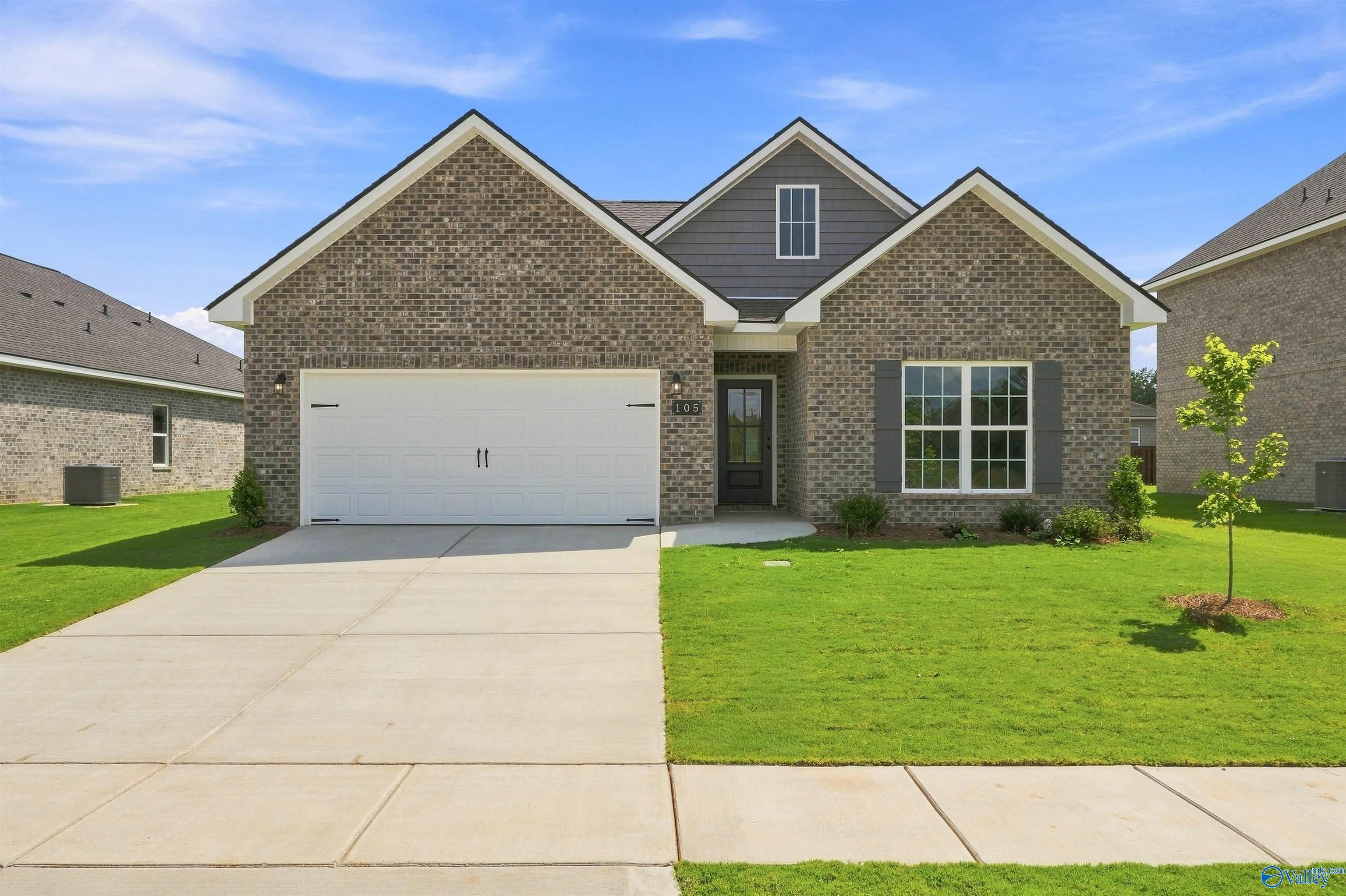 Brick front exterior with 2-car garage and landscaped yard at Davidson Homes' The Franklin C in Wood Trail, Toney, Alabama