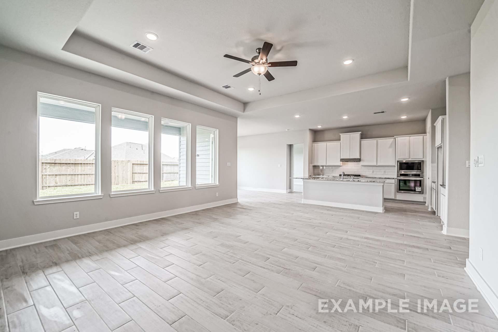 Spacious open-concept kitchen and living area in The George A home design with white cabinets, large island, and large windows