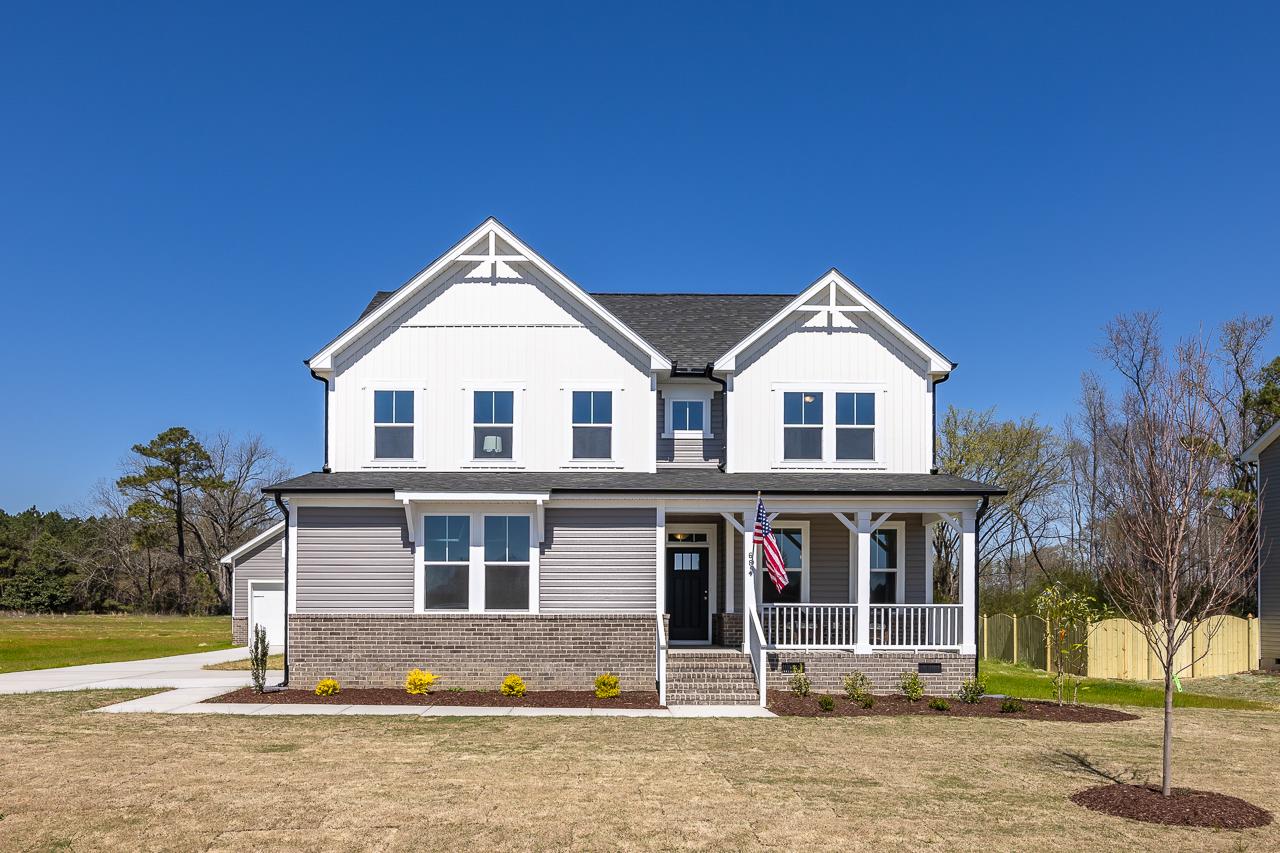 Two-story modern farmhouse home exterior at Wellers Knoll in Lillington NC with covered porch, brick base and American flag