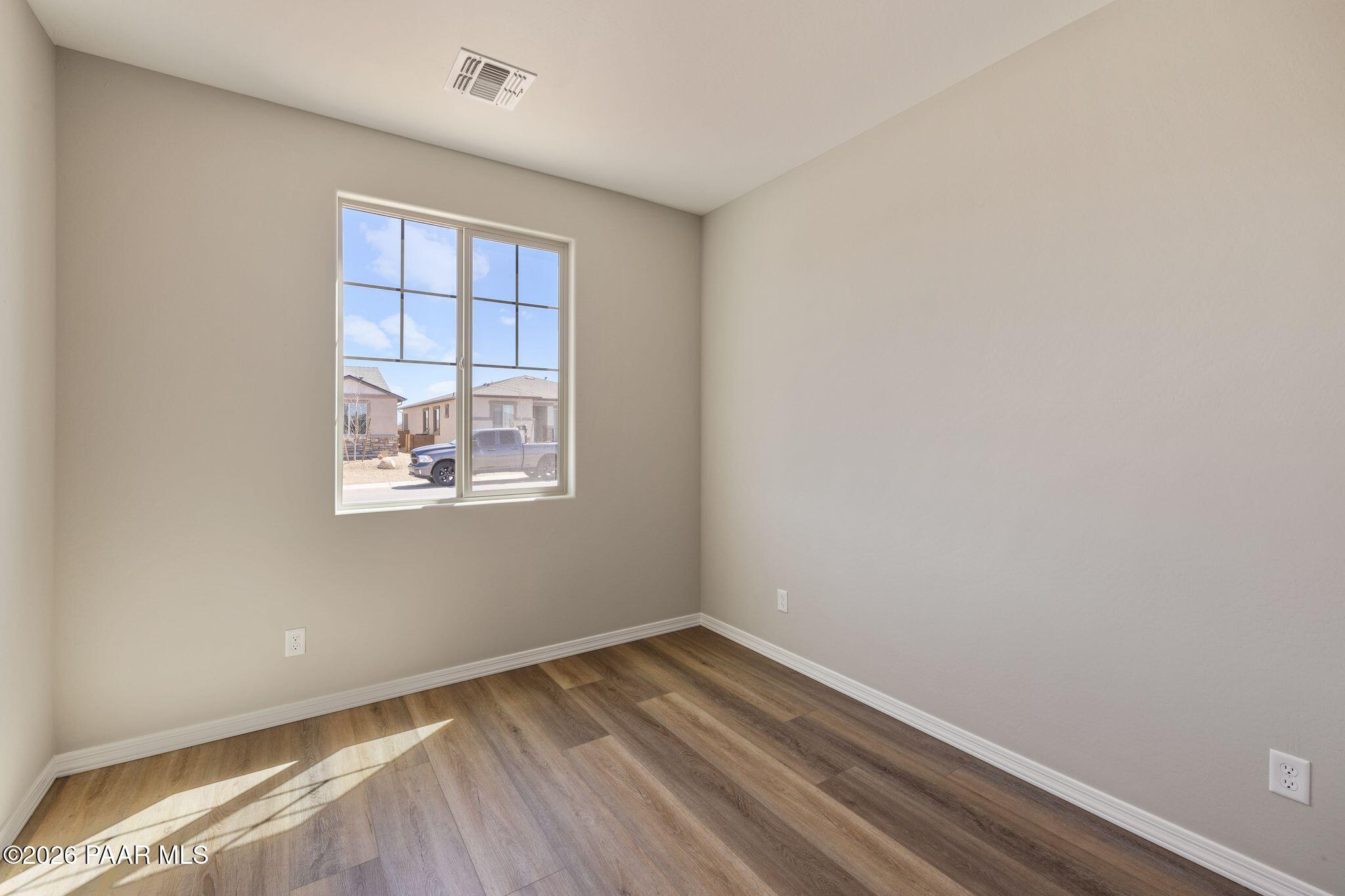 Bright secondary bedroom with large sunny window and light wood floors in Davidson Homes The Frontier A, Prescott Valley, AZ