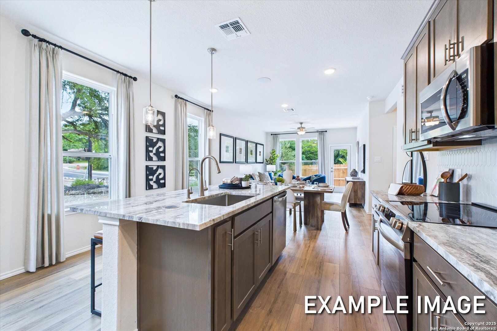 Modern open-concept kitchen with white shaker cabinets, marble island sink, stainless appliances, and adjacent dining in The Gillian C floor plan, San Antonio, Texas