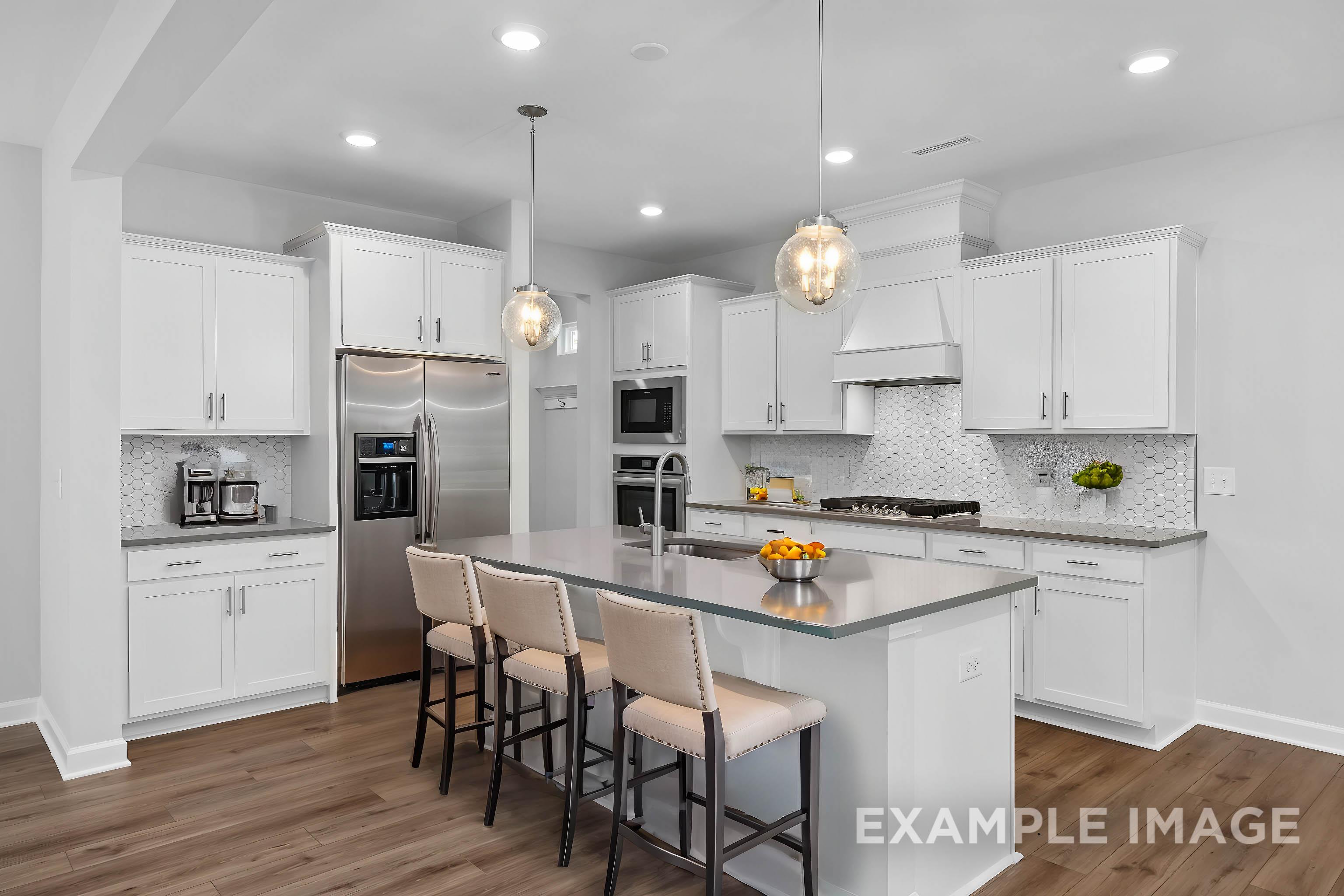 Modern gourmet kitchen in The Gavin B with white shaker cabinets, stainless steel appliances, large center island, and pendant lighting