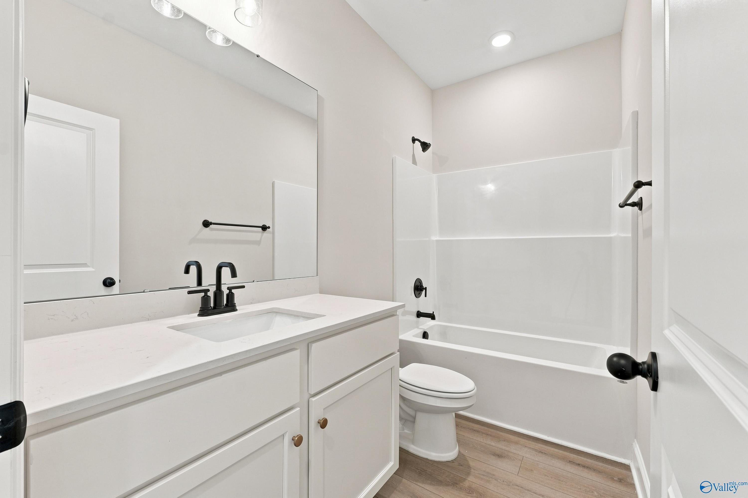 Modern bathroom with white vanity, matte black fixtures, and tub-shower combo in The Asheville E, Forest Glen, Hazel Green.