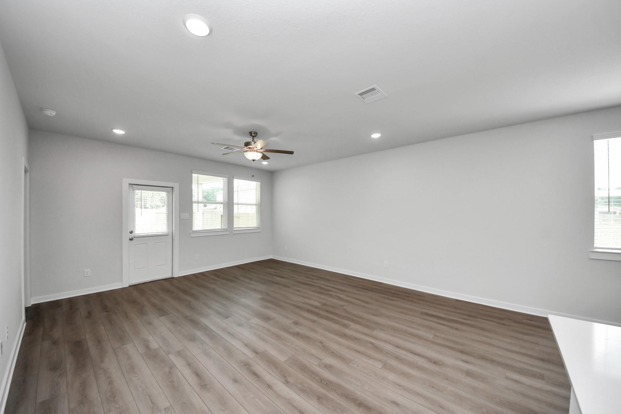 Spacious, light-filled living area with wood-style flooring in The Brazos F floor plan at Liberty Estates, Cleveland, TX.