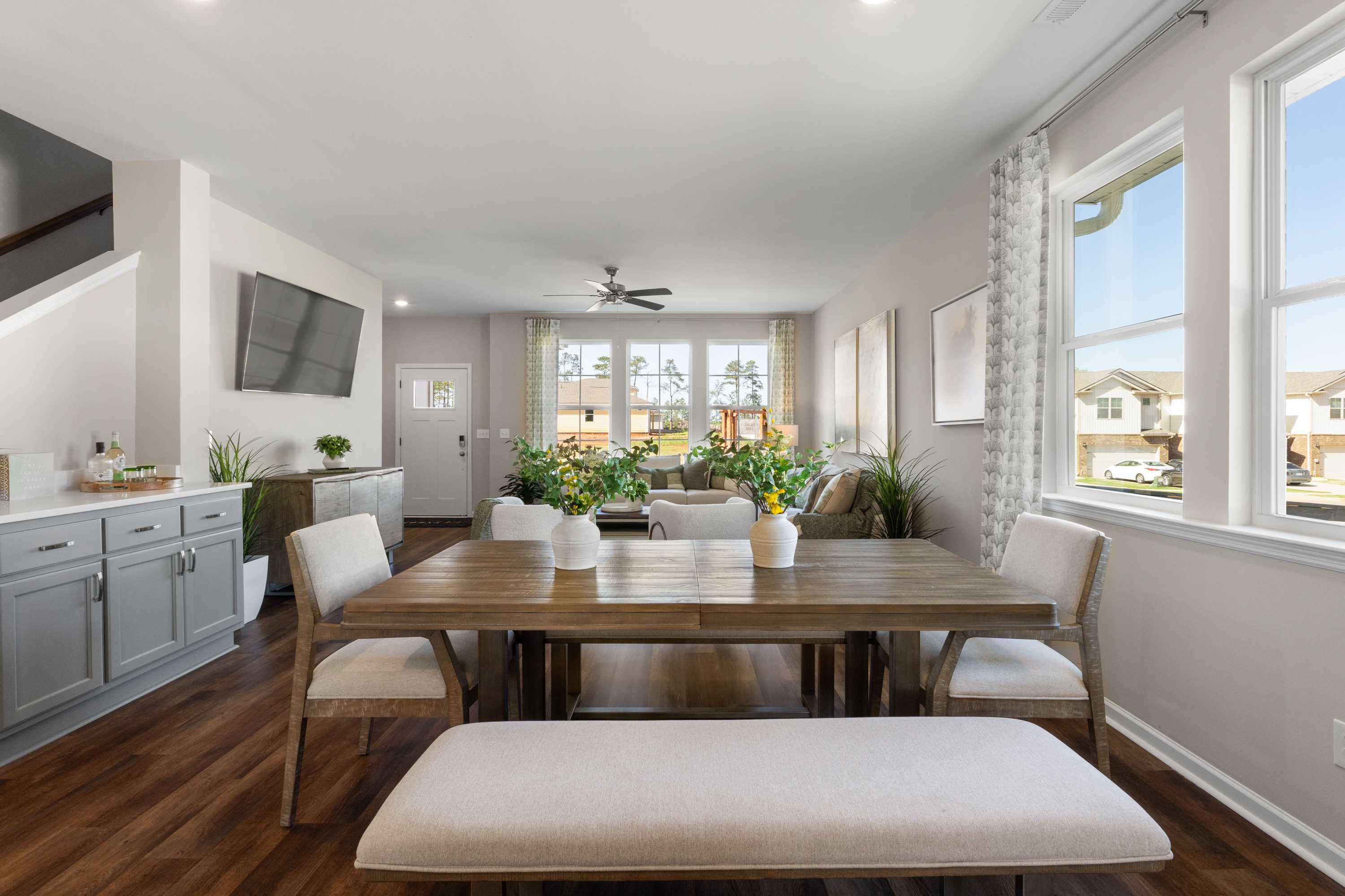 Spacious open dining area in Evergreen Mill Madison Alabama home with wooden table, upholstered chairs, large windows, and hardwood floors