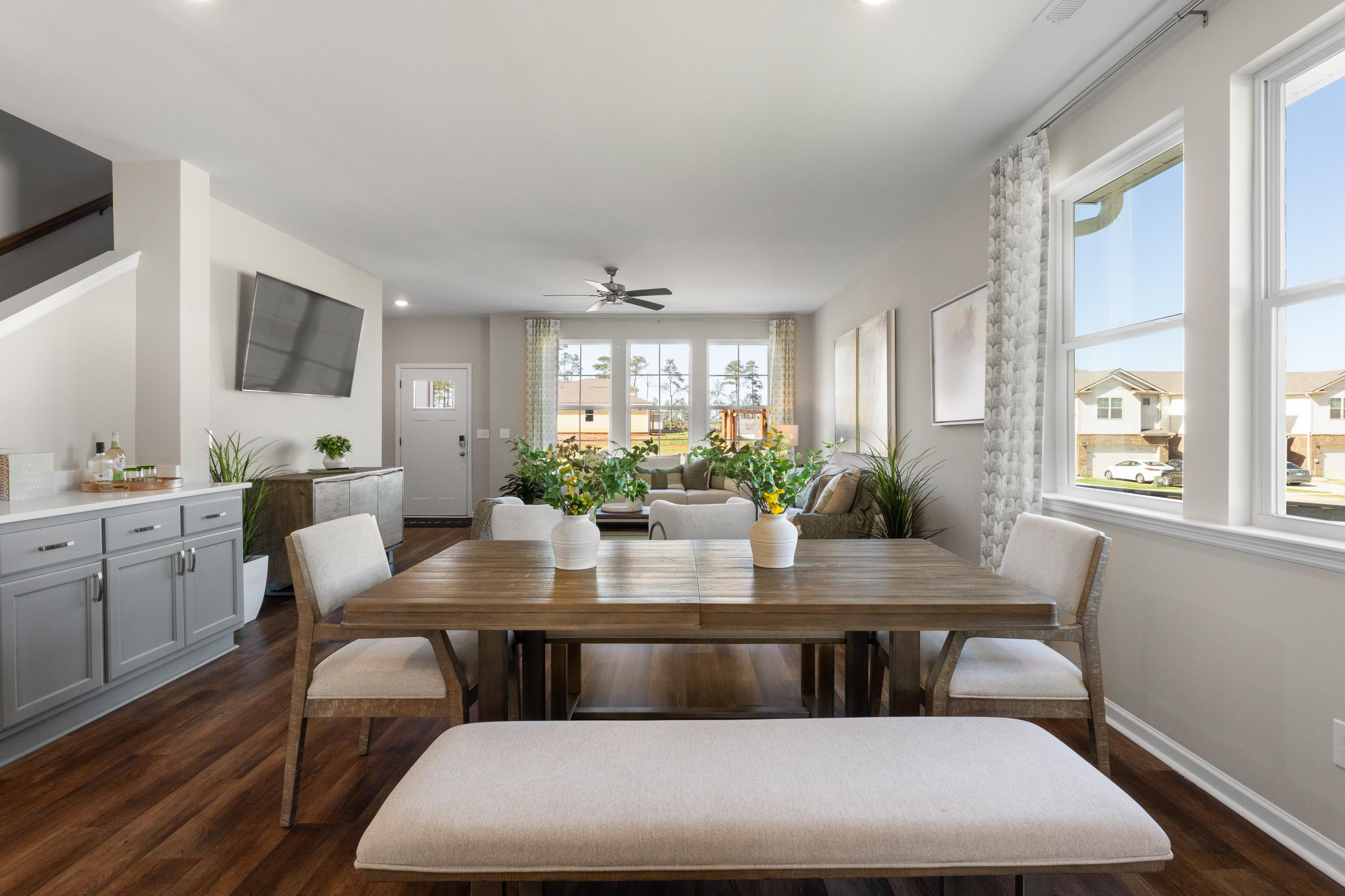 Spacious open dining area in Evergreen Mill Madison Alabama home with wooden table, upholstered chairs, large windows, and hardwood floors