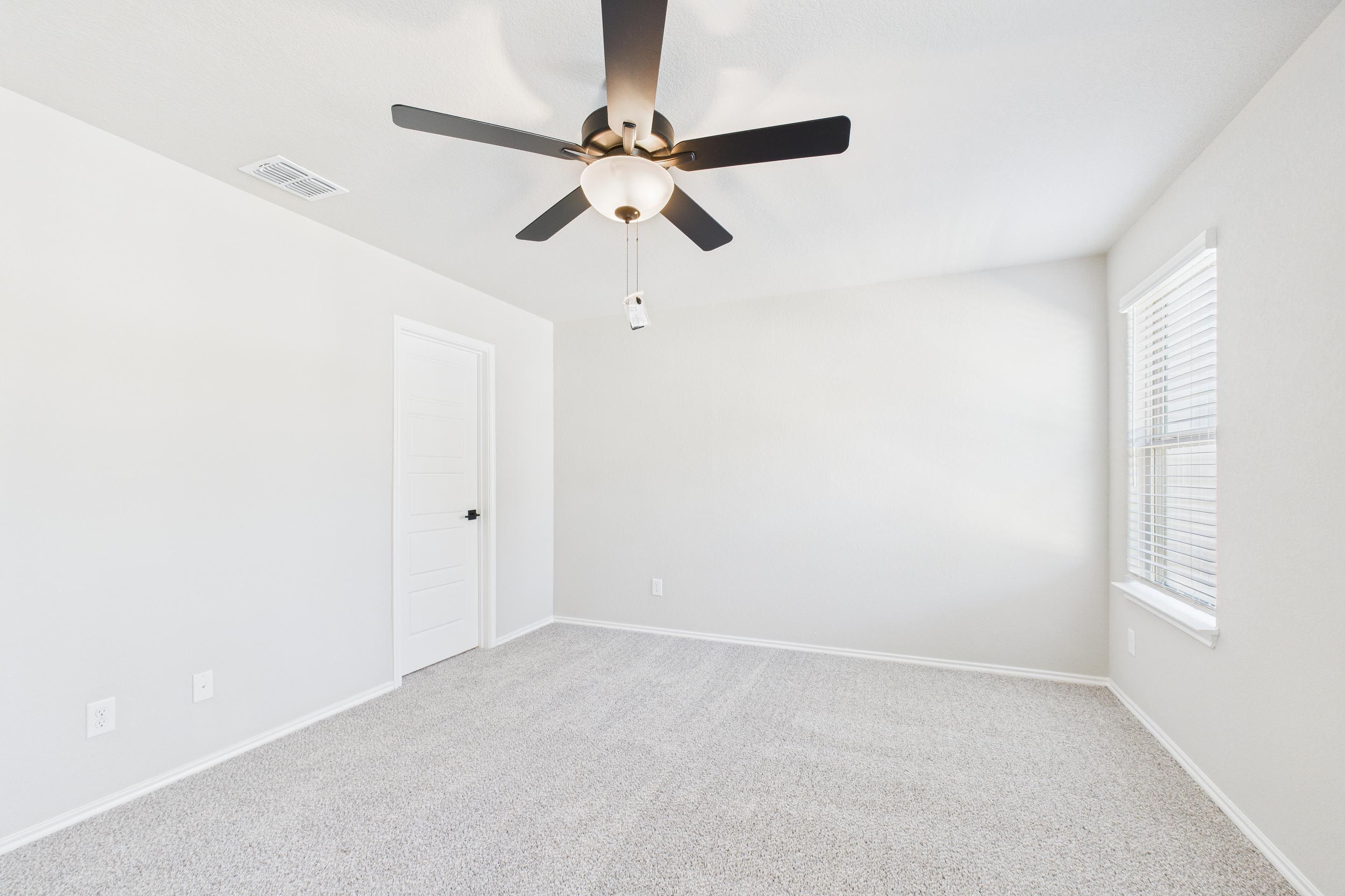 Spacious secondary bedroom in The Charlotte A featuring neutral carpet, white walls, and a modern ceiling fan.