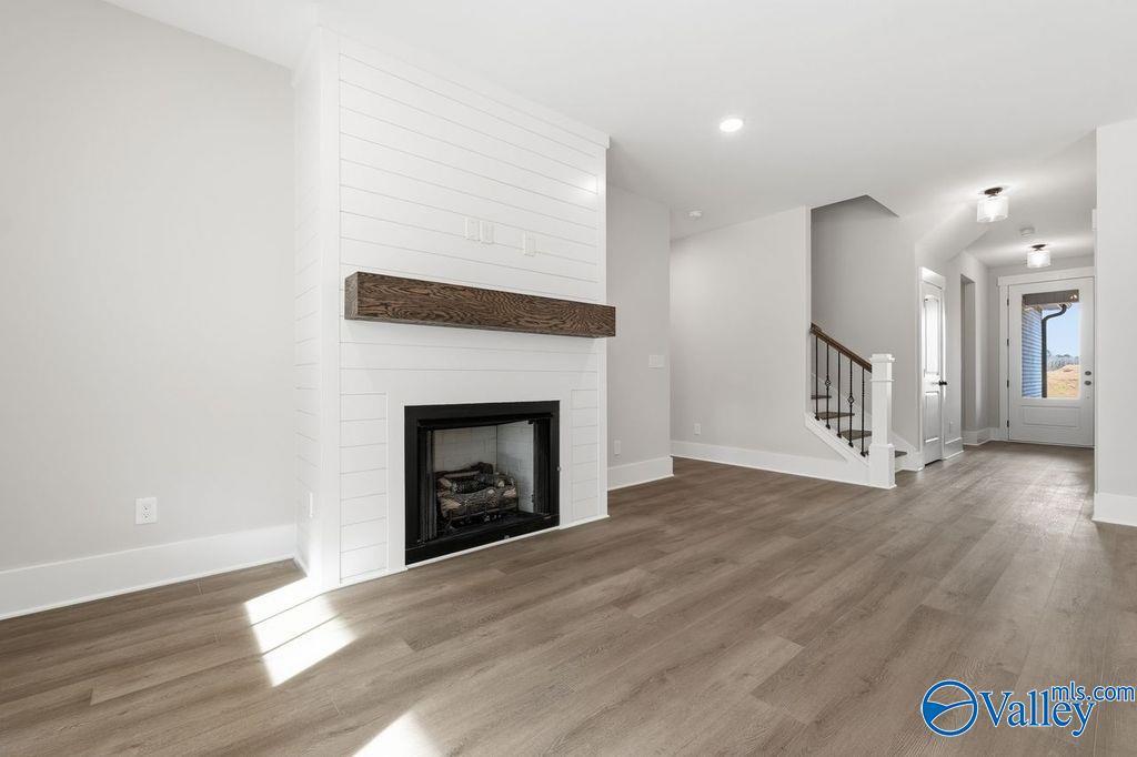 Elegant living room with shiplap fireplace, wood mantel, and open staircase in Davidson Homes The Rockford, Hartselle AL