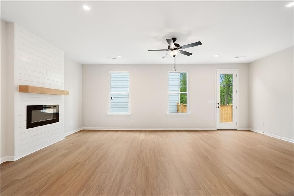 Cozy family room featuring shiplap accent wall, modern fireplace, and sliding glass door to backyard in Davidson Homes The Marion A, Kennesaw, GA