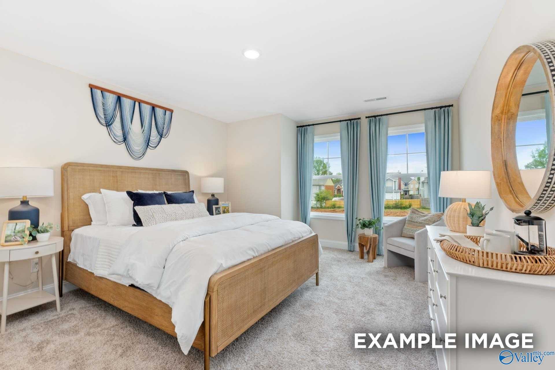 Serene bedroom with king bed, blue accents, round mirror, and plants in Davidson Homes The Camden B, Huntsville, Alabama