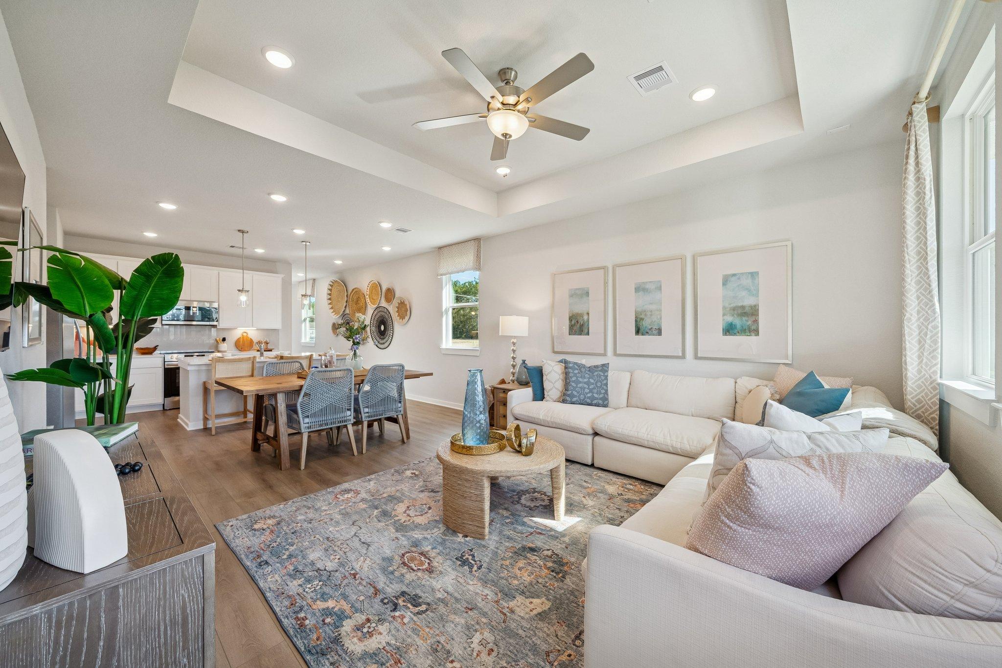 Open-concept living and dining room in Spring Branch Crossing Conroe TX with white sectional sofa hardwood floors ceiling fans and wall art