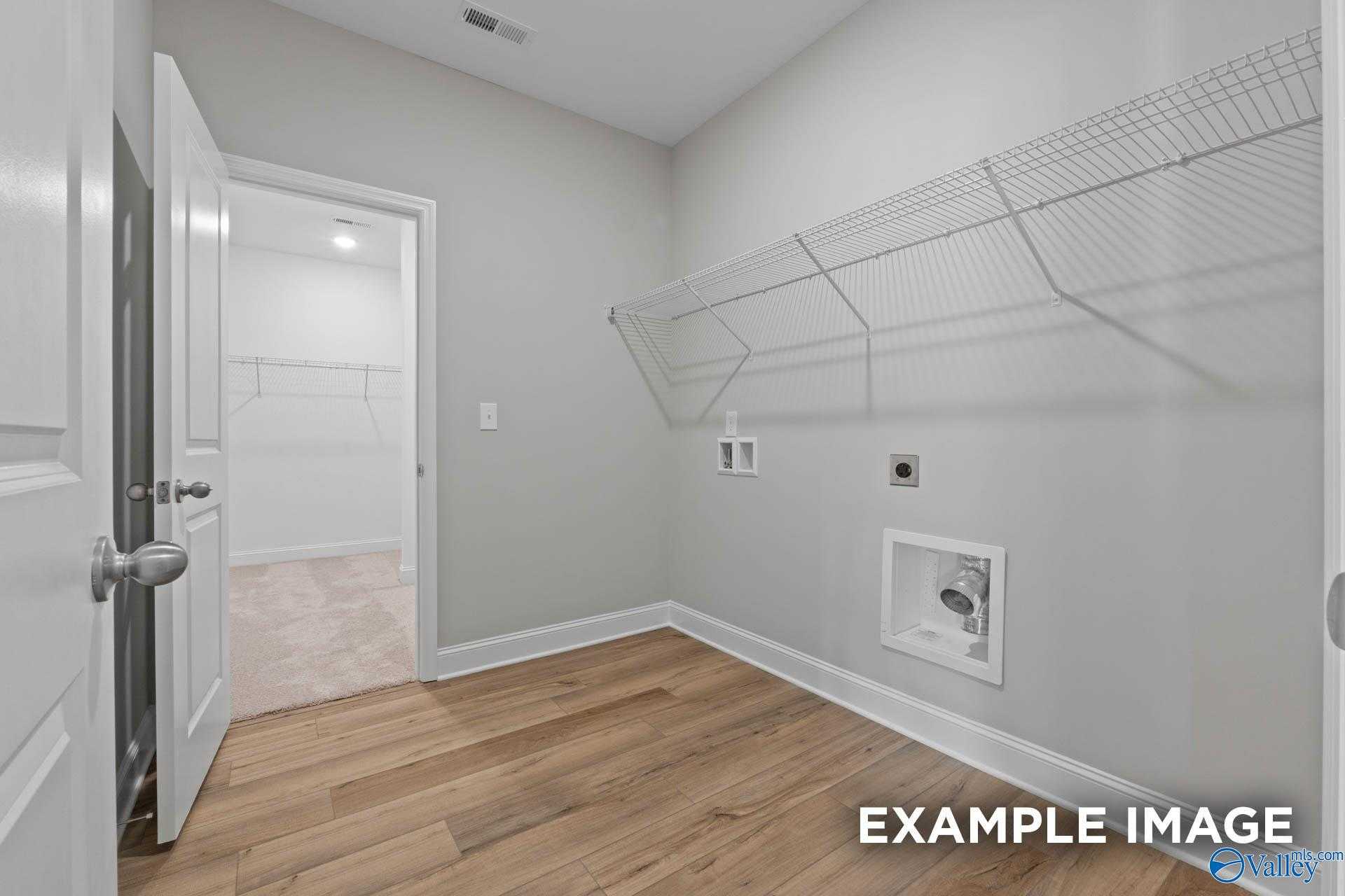 Spacious laundry room with wire shelving, washer-dryer hookups and hardwood floors in The Everett by Davidson Homes, Meridianville, Alabama