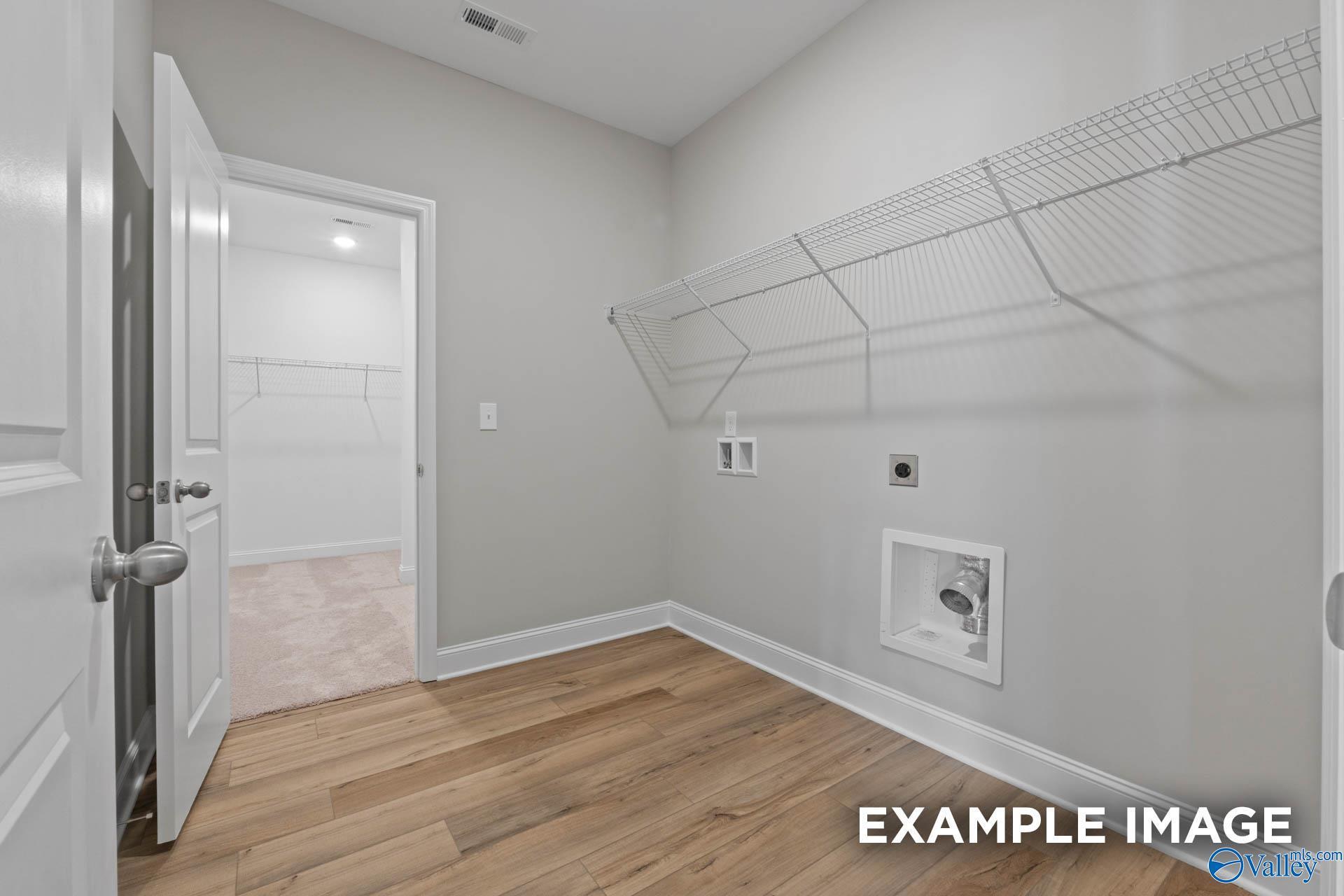Spacious laundry room with wire shelving, washer-dryer hookups and hardwood floors in The Everett by Davidson Homes, Meridianville, Alabama