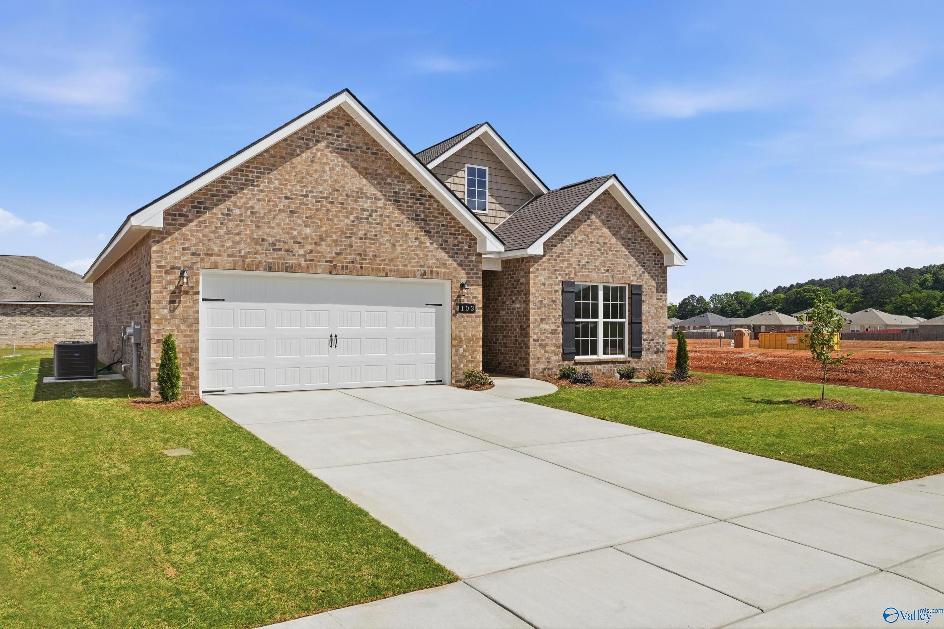 Modern brick 1-story home with 2-car garage, concrete driveway, and green lawn in Lynn Meadows, Meridianville, Alabama