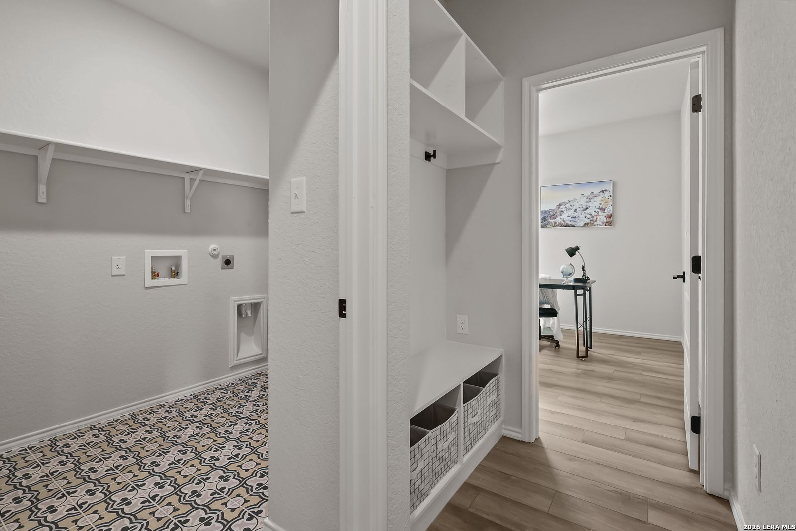 Spacious laundry room with white cabinets, utility sink, patterned tile floor, and adjacent office nook in Davidson Homes The Daphne H, Seguin, Texas
