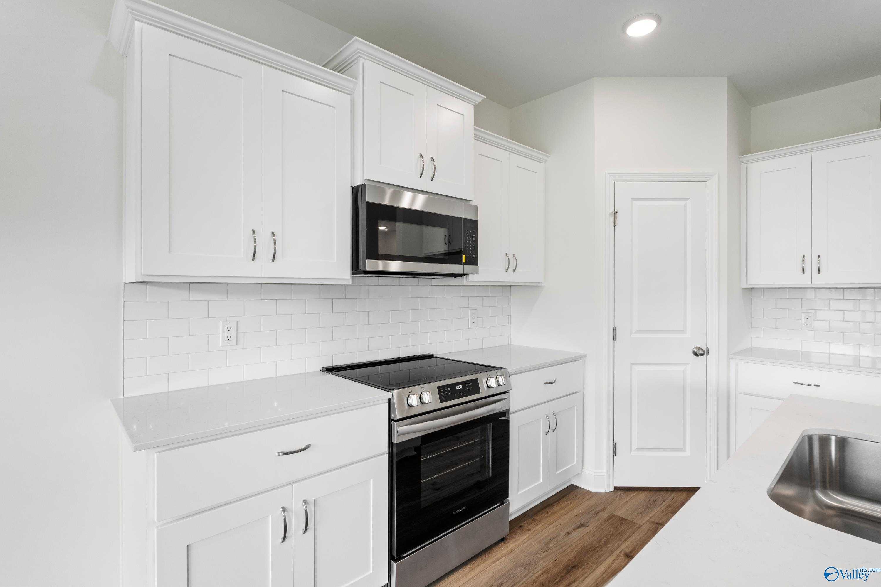 Modern white shaker kitchen with stainless steel appliances, subway tile backsplash, and quartz counters in Davidson Homes The Asheville C, Athens AL