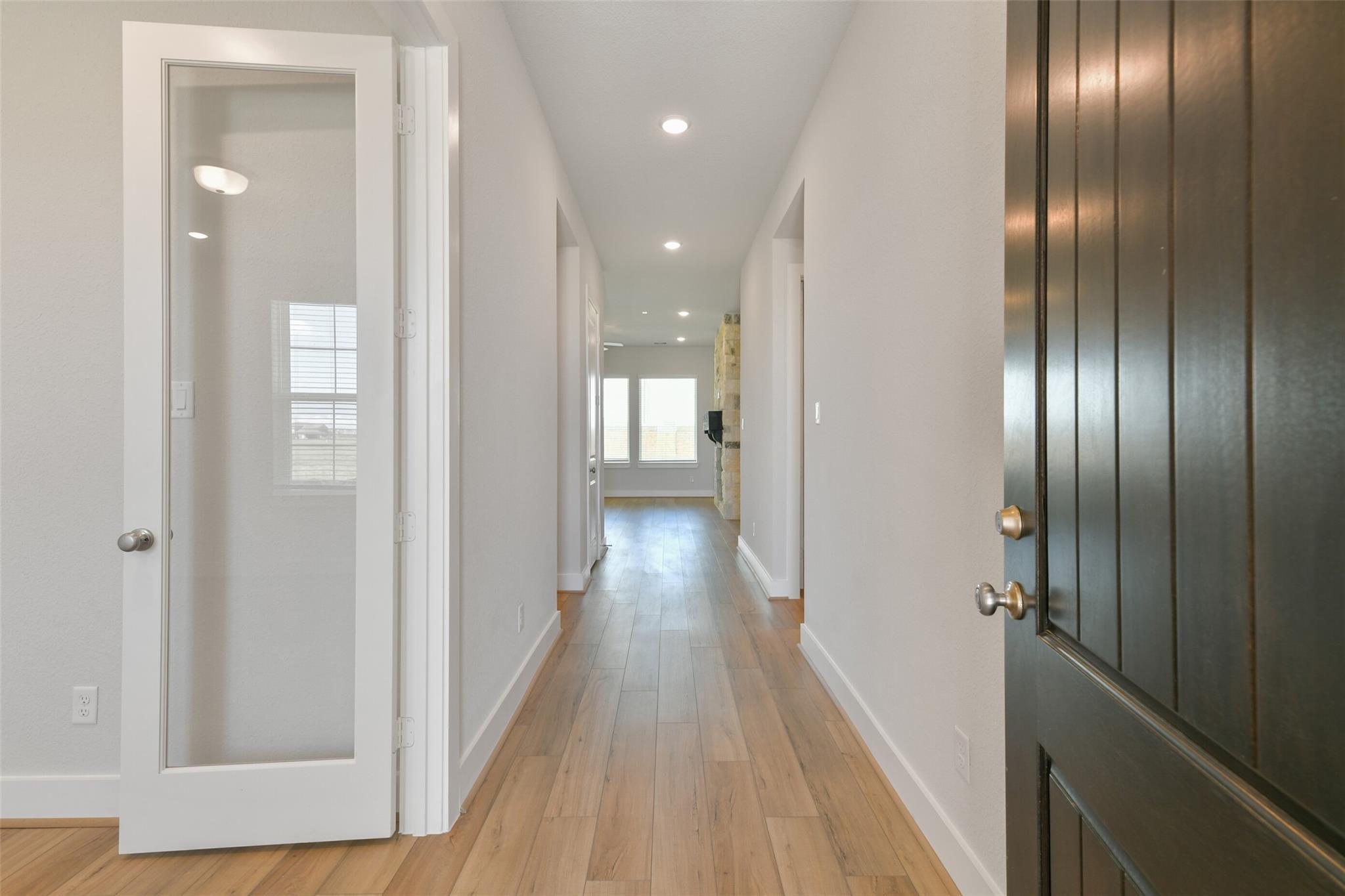 Bright hallway with oak hardwood floors, glass French doors to garage, open to kitchen in Davidson Homes The Edward A, Texas City