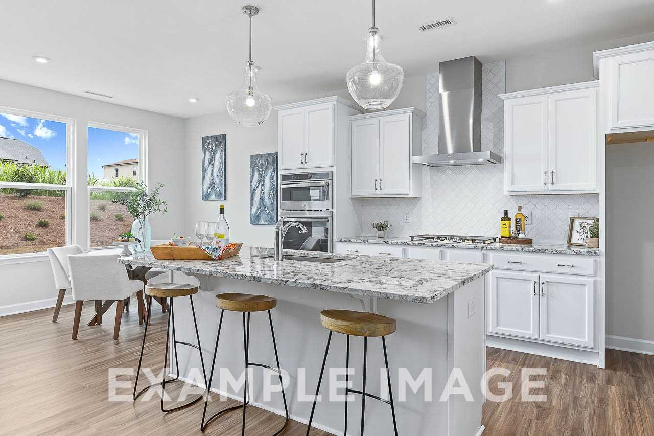 Spacious The Willow C kitchen with white shaker cabinets, granite island, stainless steel range hood, and breakfast bar stools