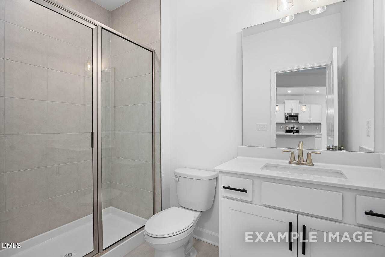 Modern master bathroom featuring frameless glass shower, white vanity, and chrome fixtures in The Willow D, Zebulon, NC